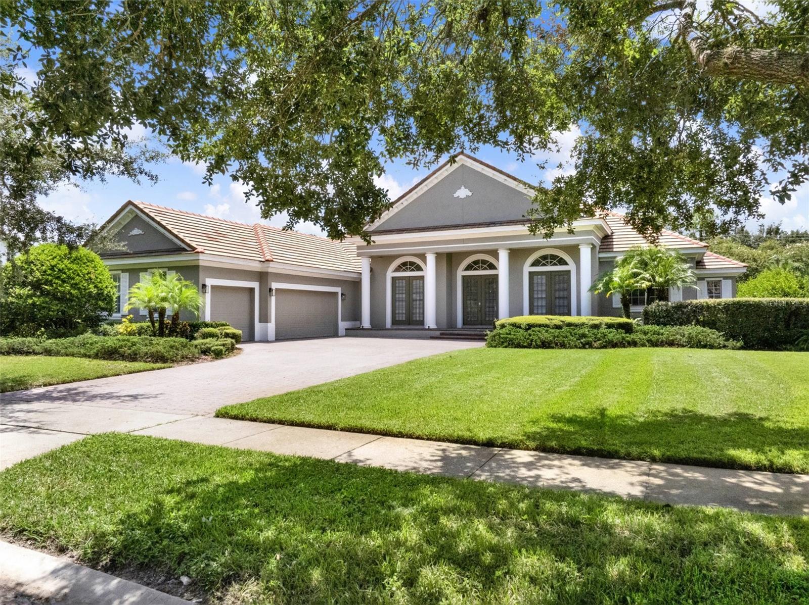 Tucked away in the prestigious guard-gated community of The Reserve at Lake Butler Sound, this exceptional 4-bedroom, 3.5-bath single-story pool home blends timeless Mediterranean style with modern sophistication. Set on over half an acre in a quiet cul-de-sac, the home welcomes you with a paver driveway, lush mature landscaping, and an elegant entry framed by architectural columns.
As you enter through the grand beveled glass French doors, you’re immediately greeted by soaring cathedral ceilings and sweeping views through the family room to the screened pool and spa beyond. The formal living and dining areas feature stately archways, tray ceilings, and designer lighting, creating a refined space for entertaining.
The heart of the home is the gourmet kitchen, designed with the chef in mind. Outfitted with granite countertops, a large breakfast bar, and a sunny dinette space, it flows effortlessly into the family room where a natural gas fireplace and rich wood floors add warmth and charm.
The spacious Owners Suite is tucked away for privacy, offering a tranquil retreat with travertine flooring, dual walk-in closets, a luxurious ensuite bath with double vanities, a large walk-in shower with dual heads, and a built-in wet bar. A flexible sitting area just outside the suite can serve as a home office, reading nook, or nursery.
Bedrooms two, three, and four offer generous space and privacy, including a jack-and-jill bath and an additional full hallway bath. A dedicated office near the front of the home can easily serve as a fifth bedroom if needed. Additional highlights include a powder room, oversized laundry room, and a 3-car courtyard-style garage.
Unwind on the ceramic-tiled pool deck surrounded by tranquil landscaping and dramatic lighting, offering a peaceful backdrop for evenings outdoors. Residents enjoy exclusive access to a community fishing pier on Lake Butler and a charming garden park, all just minutes from top-rated public and private schools, downtown Windermere, major roadways, Disney, and upscale shopping and dining.