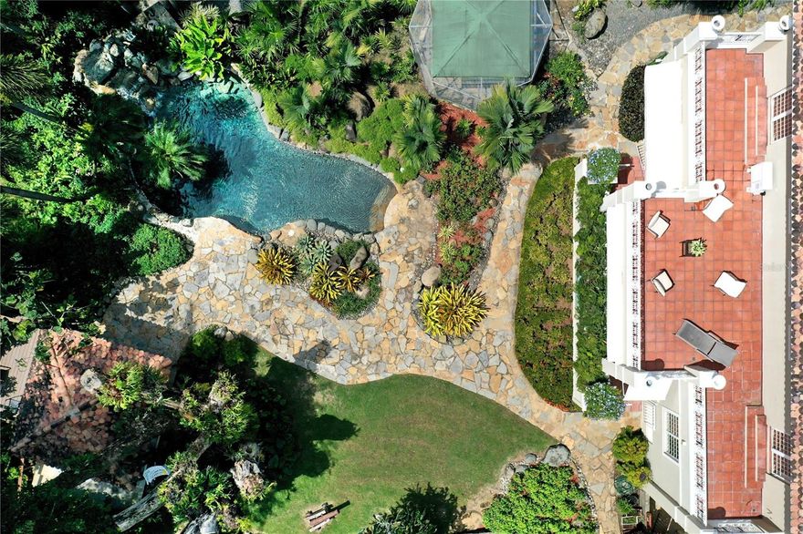 Located in the exclusive Villa Caparra community within Garden Hills, this elegant custom-built home is one of the very few in the area with a double lot encompassing 2,955 square meters.  This contemporary residence sits on a beautifully landscaped property surrounded by majestic trees and lush vegetation, with a wide variety of local and exotic fruit trees.

With an impeccable design, this Spanish-style, 2-story estate comprises over 5,585 square feet of living space with 4-bedroom suites and 4 full baths and 2 half baths.  The main level offers a grand foyer entrance, formal dining room, private office that can be easily converted into a guest room, gourmet kitchen with large center-island and adjoining breakfast nook, and generous living room with glass windows and doors that lead to an inviting terrace overlooking the pool and patio.

Linked by a staircase and an elevator, the upper level consists of 3 ensuite bedrooms that can be converted into 4, an inviting family room, and a second office.  The master, the junior suite and family room open to spacious terraces offering incredible panoramic views of the stunning natural surroundings.  All rooms are bright and airy, enhanced with oversized windows and doors.

The impressive outdoor designed by renowned Landscape Architect Gabriel Berritz, consists of sprawling lawns and a pool featuring a rock waterfall and custom lighting. The verdant landscape has a wide variety of trees and luscious tropical gardens; all providing a very peaceful and private resort style setting, ideal for both relaxed family living and large-scale entertainment.

Very private yet only minutes away from the best schools and restaurants in San Juan, this property boasts many luxurious features such as high ceilings, oversized windows, custom wood and iron work, high-quality finishes throughout, elevator, water cistern, electric power generator, and ample storage closets. This is an exceptional home that blends the natural environment with truly timeless design.