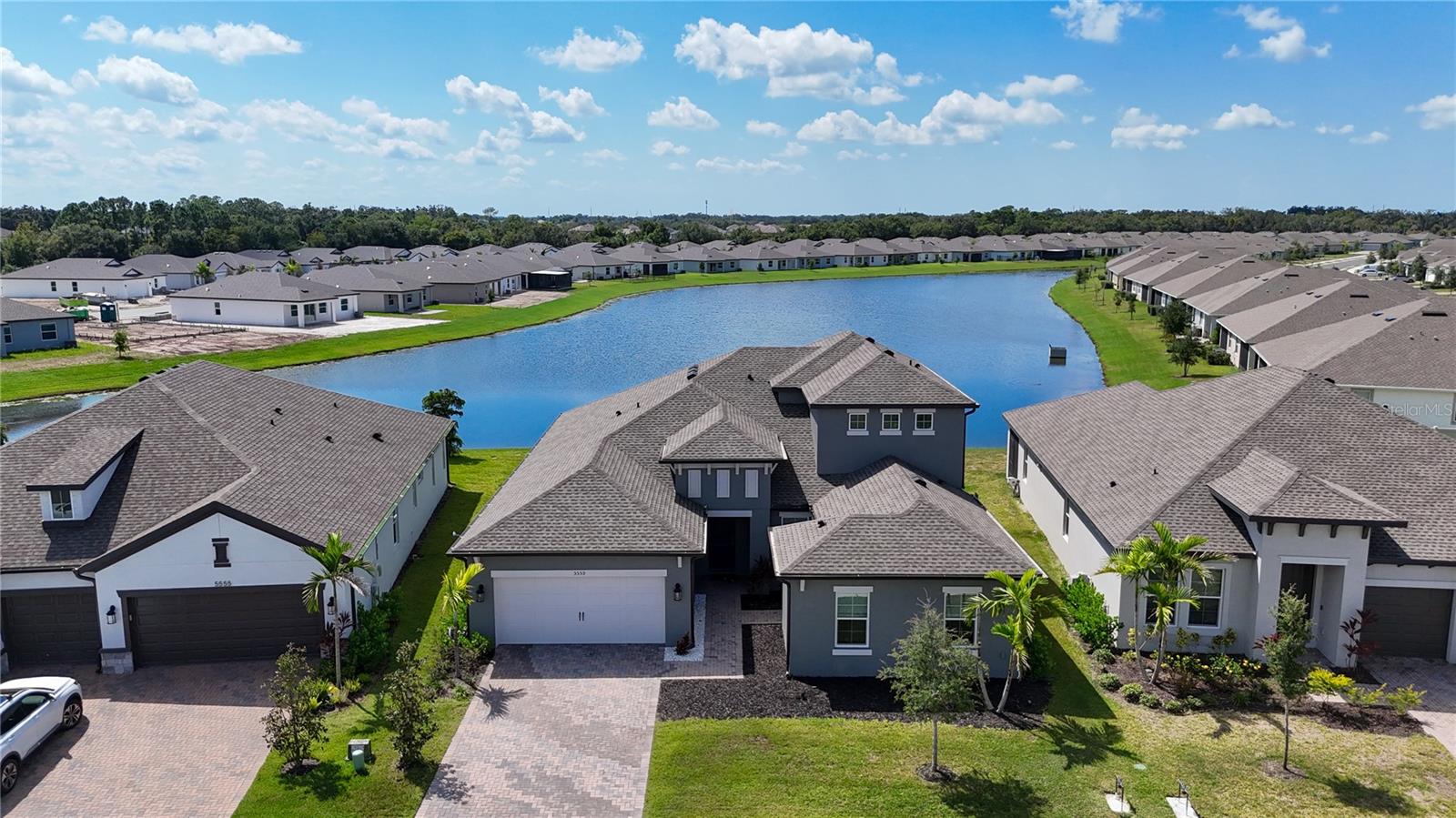Welcome to 5559 Trevesta Place, where everyday life feels like a retreat. This exceptional 5-bedroom, 5-bathroom waterfront home is a rare gem, blending elegant design, modern comfort, and resort-style living—all in one of Palmetto’s most desirable gated communities. Built in 2023, this spacious two-story home spans over 3,100 square feet and sits on a premium lakefront lot, offering breathtaking water views from the main living areas and the screened lanai. Inside, you're greeted with soaring ceilings, tray accents, crown molding, and rich stone countertops that create a luxurious yet inviting feel. The heart of the home is the designer kitchen, featuring top-of-the-line appliances, a large central island, and seamless flow into the living and dining spaces—perfect for entertaining or enjoying a cozy night in.
Upstairs, a loft with a private bedroom and bath makes the ideal guest suite, while a fully equipped in-law suite on the main floor—with its own entrance, kitchenette, and bathroom—offers unmatched flexibility for extended family or visitors. Whether you're sipping coffee on the lanai overlooking the water or hosting gatherings in your open-concept living area, every detail is crafted for comfort and connection.
Located in the resort-style community of Trevesta, you’ll enjoy exclusive access to a fitness center, zero-entry pool, splash pad, playground, and an active clubhouse with planned events. Near the beaches of Anna Maria Island, scenic preserves, top-rated golf, shopping, and dining, this home offers the perfect blend of tranquility and convenience. With hurricane-impact windows, reclaimed-water irrigation, and high-speed connectivity already in place, all that’s left to do is move in and start living your dream. This is more than a home—it’s a lifestyle. Don’t let this one get away.