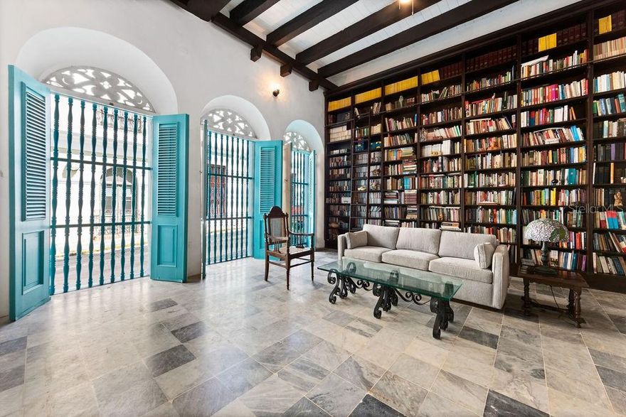 Step into a piece of history with this exquisitely renovated 2,716 SF Spanish Colonial masterpiece, nestled next to the Governor’s Mansion and steps to La Princesa Boardwalk in Old San Juan. Thoughtfully restored to preserve its timeless elegance, this two-story residence seamlessly blends historic charm with modern comforts. From the moment you enter, you are welcomed by an air-conditioned grand room with soaring 20-foot ceilings, where a full-wall library invites both quiet reflection and sophisticated entertaining. Every step through this home tells a story, with intricate tilework sourced from the historic San José Church (circa 1810), adding an unparalleled touch of authenticity and character. Original "soles truncos" archways stand as a testament to the home’s Spanish heritage, casting beautiful patterns of light throughout the space. Designed for both elegance and ease, the living room, dining area, and kitchen flow seamlessly through graceful arched openings to an indoor covered terrance and interior patio where natural light and fresh air create an inviting atmosphere for relaxation or entertaining. A conveniently located half bath is available for guests. The newly crafted wooden kitchen, equipped with brand-new appliances and a washer/dryer, is enhanced by traditional arches and stained-glass “vitrales,” adding both beauty and functionality to the space. Upstairs, you’ll find three spacious air conditioned bedrooms, three full bathrooms, and a laundry room. The two primary bedrooms feature custom closets, restored original wood floors, and double doors that open onto Old San Juan’s iconic balconies, offering picturesque views of the historic streetscape. An additional open balcony overlooks the indoor garden, providing the perfect spot to unwind. The property includes a full-power generator and a water cistern for added convenience and reliability. Ideally located on San Francisco Street, this exceptional home offers both security, with a police station directly across the street, and convenience, just a short walk from the San Juan Cathedral, Plaza de Armas, and an array of fine dining restaurants. A rare opportunity to rent a true Old San Juan treasure, this residence is a perfect blend of history, charm, and refined living.