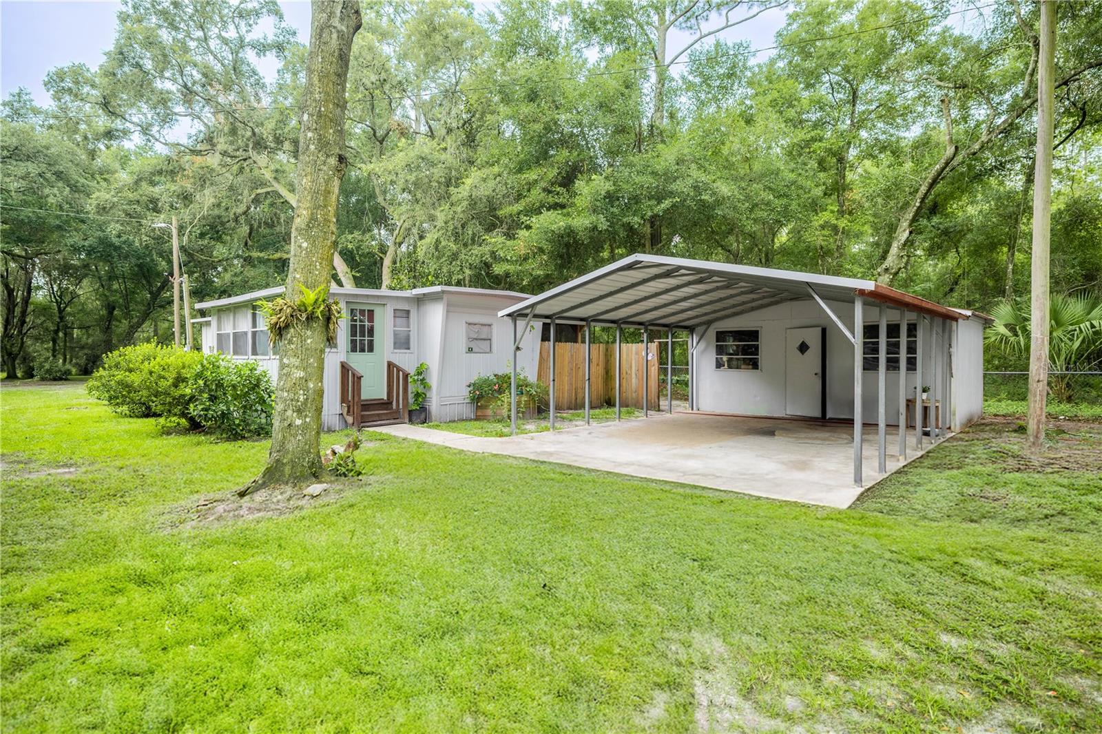 Spacious corner lot with investment potential in Silver Springs! This 2-bedroom, 1.5-bath 1965 mobile home offers 782 square feet of living space on a fully fenced 0.65-acre corner lot, made up of three separate parcels. The home backs up to a peaceful, treed lot, offering added privacy and a natural view. Inside, you'll find a bonus room perfect for an office, hobby space, or guest area. Outside features include a 2-car carport, two storage sheds, and an RV hookup. The quiet neighborhood offers a serene setting, and the road remains accessible even after storms—ideal for year-round living. Located just minutes from the Ocala National Forest, Silver Springs State Park, and several nearby springs, this home is perfect for nature lovers or anyone looking to be close to outdoor adventure. Whether you're seeking a primary residence, a weekend retreat, or a smart investment, the extra land gives you flexibility to expand, build, or sell parcels individually. A rare opportunity offering space, privacy, and potential all in one!