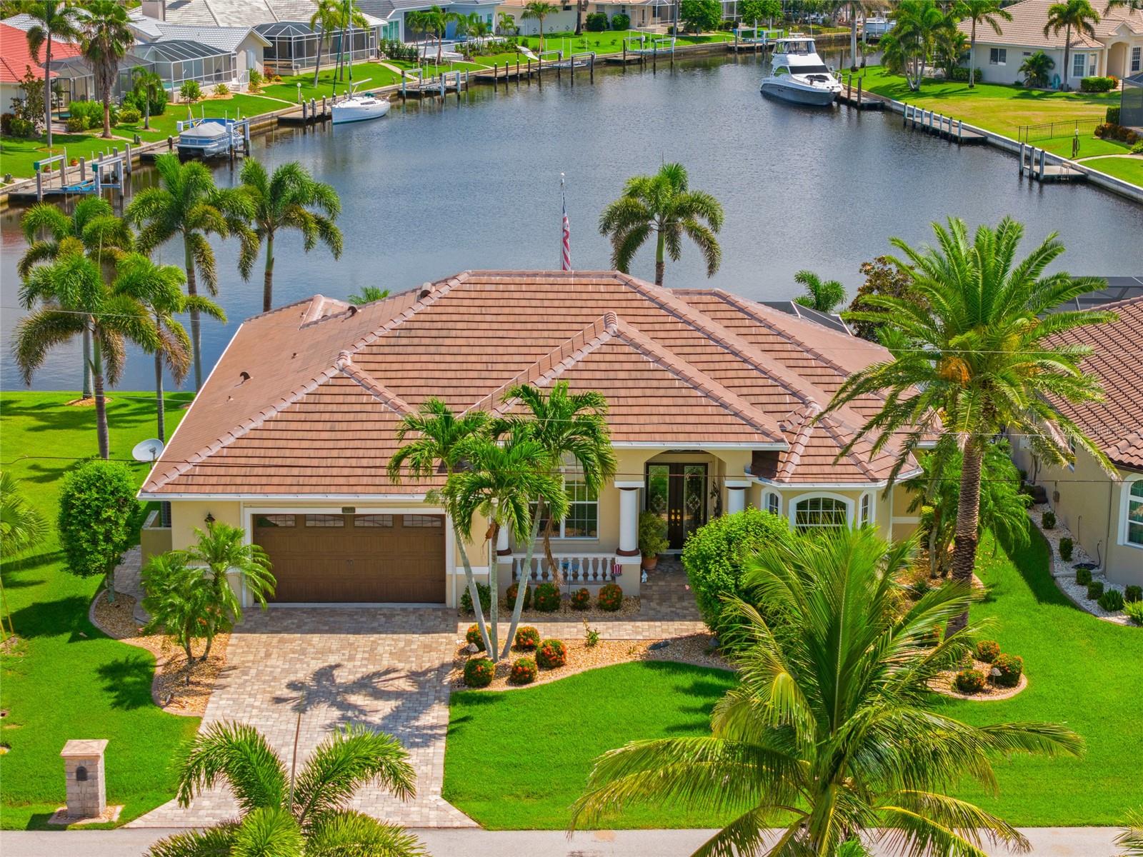 PRICED TO SELL! BURNT STORE ISLES! BEAUTIFUL 3 BEDROOM, 2 BATH, OVERSIZED 2-CAR GARAGE, WATERFRONT, POOL HOME WITH SAILBOAT ACCESS TO CHARLOTTE HARBOR LEADING TO THE GULF! Nestled on a quiet street with lush tropical landscaping and stunning water views. Step inside through the double door entry to an open floor plan that features high ceilings and neutral décor creating a bright and airy ambiance throughout. The kitchen is equipped with raised-panel cabinetry, granite countertops and backsplash, an induction stove, stainless steel appliances, breakfast bar, and large aquarium window overlooking the pool and water views. The spacious family room offers access to the lanai with zero-corner sliding doors for indoor/outdoor entertaining. Retreat to the primary suite, which includes access to lanai, his and her walk-in closets, and private bath with dual sinks, a seated vanity, garden tub, and private shower. The split floor plan ensures privacy for all, with two guest bedrooms and a separate bath with vessel sink. Outdoor living is a highlight here, with a covered lanai and a panoramic screened heated pool and spa. Enjoy the convenience of a summer kitchen perfect for hosting. Form the lanai, a path extends down to the private dock, complete with water, electric, marine tower, fish cleaning table and breathtaking water views—perfect for fishing or simply soaking in the beautiful surroundings. Additional highlights include plantation shutters, pool chair lift, central vac, workshop and AC in oversized garage. Located in a popular deed-restricted boating and golf course community, this home offers optional memberships at the nearby Twin Isles Country Club. Enjoy an 18-hole championship golf course, swimming pool, tennis complex, and a spacious clubhouse with dining and social events. With easy access to I-75 and a short drive to restaurants, shopping, The Yacht Club, Fishermen's Village, and historic downtown Punta Gorda, this home is truly one of a kind. Don't miss out on the opportunity to make this beautiful home your new Florida retreat. Schedule your private showing today!