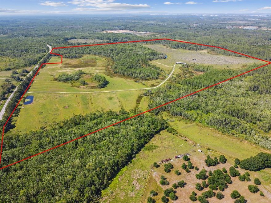 The HWY 557 Lake Alfred property (Parcel ID: 262708000000012010) spans 305 acres, with approximately 92 acres of developable land, and is strategically located just 45 minutes (39.6 miles) from Orlando International Airport and 38 minutes (27.3 miles) from Walt Disney World. Currently zoned for agriculture at one dwelling unit per five acres, the site yields about 20 lots, but its contiguity to the City of Lake Alfred offers a strong opportunity for annexation, unlocking access to city water and sewer and enabling rezoning to a much higher density. With a Village Residential designation allowing four units per acre, the property has a projected yield of roughly 408 units. Directly across SR 557, Meritage Homes’ Silver Lakes community has already extended water and sewer infrastructure to their entrance, enhancing feasibility for development. CR 557 is scheduled to be widened to four lanes beginning in summer 2025, with completion expected in three years, and a roundabout will be added at the intersection of CR 557C and CR 557 to improve traffic flow. A five-acre retention pond adjacent to CR 557 will slightly reduce the total developable acreage. The property sits within an active development corridor with major builders such as Pulte, DR Horton, Meritage, and American Homes driving growth, and additional utility extensions by nearby projects will further support development. While the site benefits from strong accessibility and regional demand, considerations include its location within a 100-year flood zone requiring fill and flood insurance, areas of poorly drained soil, and an irregular parcel shape that may constrain layout and reduce final lot yield. Entitlement approvals for annexation, land use amendment, and rezoning are required, but all have a high probability of success and can be pursued concurrently, with an estimated approval timeline of six to twelve months.