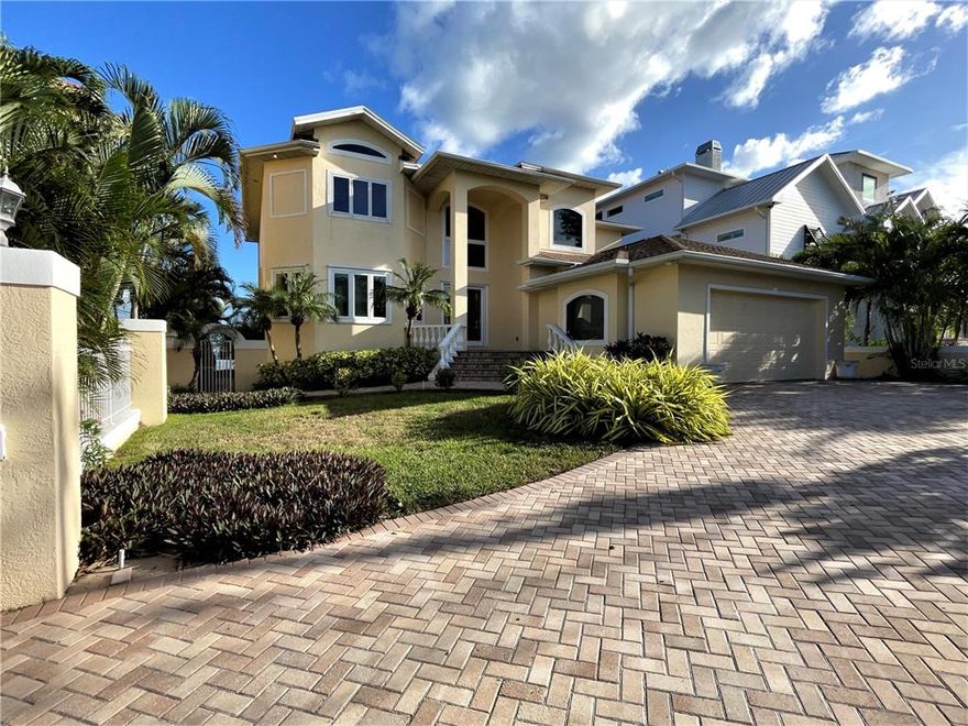 This light and airy, custom-built, elevated, Intracoastal, pool home, has a panoramic view across 4,000 feet of water, a 75’ newer seawall, dock with composite decking, boat lift, and on a deep-water, no wake channel. Property is located approximately 600 yards from a resident only parking at a semi-private sandy beach and the azure, warm waters of the Gulf of Mexico (less when using footpath) and just steps from a park with playground and tennis courts. The home has a good combination of architectural flair and functionality; the main living area has 20-foot ceilings, an array of sliders & picture windows that flood the home with light and a water view from most areas of the interior. The spacious master and guest suites have water views and balconies. The split-plan design separates the second-floor master and guest suites by an elegant balcony. A ground floor bedroom has sliders opening onto the pool patio area. The master en-suite bedroom has a tray ceiling, bathroom with luxury tub & shower, granite topped vanities, and spacious his & her walk-in closets. The island kitchen has stainless steel appliances, large eat-in area, quality wood cabinetry with granite tops, writing desk and gas cooktop on island. The L-shaped living area has a gas burning fireplace, bar, formal dining and 21” marble tile. A bathroom and powder room can be accessed directly from pool area. There is a laundry room with utility sink and large closet. Generous closet storage throughout the home. The home has an off-road frontage view, walled yard and spacious paved drive that provides additional parking, electrical wiring installed for an entry gate. The oversized, raised paved patio, has a deep-water pool & spa. Home has an electric standby generator, concertina storm shutters & protective film on windows, newer seawall, speakers installed throughout, security system, custom millwork, and central vacuum. Click tour button to view video walk-through.