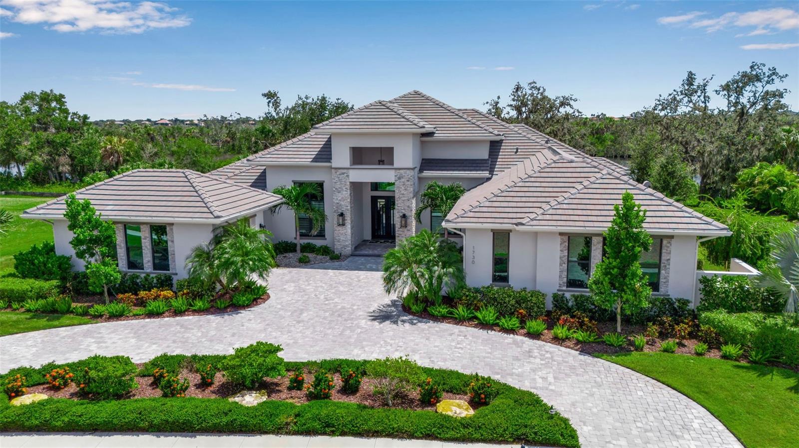 Discover a luxurious blend of craftsmanship, comfort and elegance in this custom-built Arthur Rutenberg waterfront estate with a private boat lift and pool/spa located in The Islands on the Manatee River - one of the most prestigious and sought-after guard-gated boating communities. Designed to capture the essence of Florida living, this exceptional residence sits on a southern-facing, half-acre lot with stunning views of the river, offering direct boating access with no locks to the Gulf. From the moment you step through the double iron doors, the detailed foyer entry with wood inlay flooring sets the stage for the refined design and thoughtful details throughout. Built to high-quality standards and spanning nearly 4,000 square feet of air-conditioned living space, this home features 4 spacious bedrooms, each with its own en-suite bath, a dedicated home office and an inviting bonus room. Soaring 12-foot ceilings, solid 8-foot interior doors, impact-tinted glass windows, custom closets, crown molding, high-end lighting and rich wood flooring set the tone. The heart of the home is the impeccable chef’s kitchen, outfitted with top-of-the-line Monogram stainless steel appliances, including a 6-burner dual-fuel range, built-in oven and microwave, 42-inch built-in refrigerator and wine fridge. A large walk-in pantry hidden behind a custom cabinet door, quartz countertops, high-end cabinetry, a massive island with additional storage and a wood-accented double tray ceiling with chandelier, ensure both beauty and functionality. The kitchen overlooks the family room with an elegant electric fireplace, coffered ceiling with wood accents and expansive impact-resistant pocketing sliding doors with access to the covered lanai and pool/spa. The travertine-tiled lanai is designed for entertaining, with a fully equipped outdoor kitchen featuring a Lynx gas grill, vent hood, sink, fridge, custom cabinetry and quartz counters. Lounge under the wood ceiling with triple outdoor fans, gather around the gas fireplace, or unwind in the 17,200-gallon saltwater pool/spa - all framed by a picture-view screen cage that maximizes your panoramic water views. The Mosquito Masters system adds another layer of outdoor comfort. For boating enthusiasts, the 36-foot private dock with 14,000-pound lift, electric, water, lighting, and walkway to the lanai is a rare luxury - offering seamless access to the river and Gulf. The primary suite is a serene sanctuary featuring oversized French doors to the lanai, tray ceilings, custom drapery and shades, dual walk-in closets and a spa-inspired bathroom with a freestanding soaking tub, double vanities with makeup station, walk-in shower, water closet and access to a secluded garden patio - a rare and peaceful escape. Additional bedrooms are thoughtfully separated for privacy, each offering their own en-suite bathrooms and walk-in closets. Work from home in the dedicated office/den with floor-to-ceiling windows, 14-foot ceilings and custom millwork. The oversized bonus room overlooks the pool and river – making it an ideal space for a media room, lounge or game space. The laundry room is equipped with Samsung washer/dryer, custom cabinetry, utility sink, and natural light pouring in through oversized windows. The 3-car garage features epoxy floors, custom storage cabinetry and a 2-foot extension on both bays. This is more than a home - it’s a lifestyle destination for those who value privacy, quality, and direct boating access.