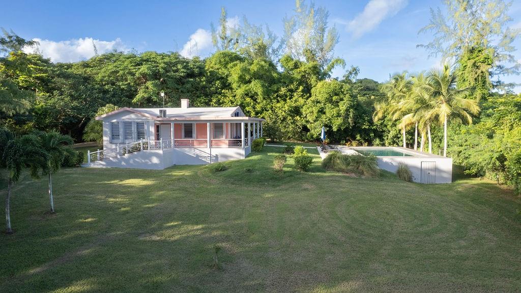 Located in the natural and quiet neighborhood of El Pilón, La Escapada is a homestead-like property with 1.8 acres of impeccably maintained land, surrounded by lush vegetation that includes mature trees such as coconut palms, majestic Guanacaste trees, towering Pines and a beautiful Ceiba. Built towards the back of the lot, the house is protected by a green environment that guarantees complete privacy and tranquility.
La Escapada is home to a large, luxurious travertine pool equally great for doing laps, diving in, and poolside entertaining. Surrounded by a spacious terrace, the outdoor living area is ideal for enjoying the tropical weather, stargazing, and private relaxation surrounded by the natural landscape. Its wraparound, covered veranda provides a comfortable and breezy outdoor place to rest, read, and enjoy the sights and sounds of nature. Access to the property is through an elegant entrance with a unique bridge, that leads to a fully paved driveway and covered carport.
Inside, the mint condition house has an open design that unites the living room, dining area and kitchen, creating a comfortable and bright space, cooled by a quiet air conditioner. The high, vaulted concrete ceiling provides a feeling of spaciousness and elegance. The amply-sized kitchen is equipped with dark wood-finish cabinetry and a beautiful tiled backsplash. The two large bedrooms both have AC, floor-to-ceiling closets and light-blocking windows that can be opened up to enjoy the natural light and outdoor greenery throughout the day. The two modern bathrooms are equally spacious with a skylight that allows in natural light.
Finishing touches to the recent renovation are the new windows throughout the home and a spacious outdoor shower offering total privacy. Further making this home move-in ready are furnishings that include king size beds, dressers, nightstands, dining table and custom full-length mirrors in the bedrooms. Whether you're seeking peaceful solitude, a space for entertaining, or a seamless connection to the outdoors, this meticulously designed property provides it all. A perfect fusion of comfort, style, and natural beauty.