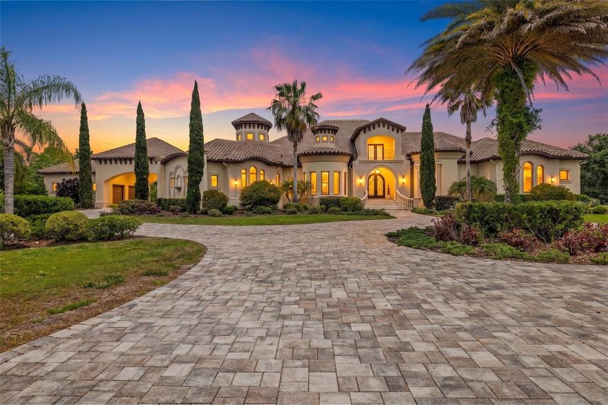Behind the gates of Steeplechase—one of Odessa's most desired luxury communities—sits a residence that has never before been offered to the market. Custom-built in 2015 and held by its original owners ever since, this 6,875 sq ft estate represents a rare opportunity: a home built with intention, and maintained with pride across 2.77 acres. The story begins at the entrance. Ceilings rise to 20.5 feet, and the grand foyer sets a tone that carries through the entire home—volume, light, and a sense of arrival that simply cannot be replicated in standard production construction. Beyond the entry, the floor plan unfolds into expansive living spaces designed for both everyday family life and entertaining at scale, with sightlines and proportions that feel as considered as they are comfortable. Stone is the signature of this home, and it has been executed at the highest level. Marble flooring runs through the majority of the interior, an installation valued at $240,000 in today's market, and continues into every shower, giving the baths a spa-like experience. The kitchen pairs an honed granite island with rich onyx quartz countertops, while that same onyx quartz reappears as a dramatic feature wall in the game room, tying the home together as a single, cohesive design statement rather than a series of disconnected rooms. Interior and exterior surround sound is wired throughout, ready for everything from quiet evenings to weekend gatherings. Five bedrooms and six full baths provide generous, flexible accommodation, and a four-car garage answers the practical needs of a fully equipped household. Just as important is what you don't see: solid concrete block construction and impact-rated windows and doors throughout—the structural fundamentals that discerning Florida buyers prioritize, delivering storm-season peace of mind. The outdoor living is where this estate truly distinguishes itself. A 1,447 sq ft covered lanai extends the living space into the open air, anchored by a fully covered outdoor kitchen built for serious entertaining. Beyond it, a heated saltwater pool and spa invite year-round enjoyment, framed by the privacy of 2.77 acres. And the location is exceptional. Steeplechase places you in the heart of Odessa, with everyday essentials, grocery, coffee, and the dining and shopping of Westchase and the Veterans corridor all just minutes away. When the wider world calls, Tampa International Airport is only 25 minutes from your gate. Homes of this caliber—original-owner, custom-built, and finished to this standard—rarely come to market in Steeplechase. This is a singular offering of scale, craftsmanship, and premium materials in one of Odessa's most desirable gated enclaves, ready for its next chapter.