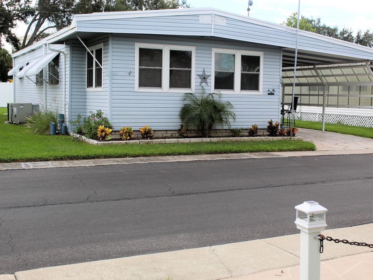 A well-maintained, updated double-wide mobile home featuring two bedrooms and two bathrooms is now available in the pet-friendly section of Palm Hill Mobile Home Park. There’s even a patio in the backyard with lush green space beyond and no rear neighbors. Palm Hill’s one monthly fee of $554 covers a lot- water, sewer, trash, recycle pickup, lawn care, cable, and internet. The community has endless opportunities for enjoyable living. Pools, Jacuzzis, tennis, pickleball, golf, shuffleboard, and social events at the two clubhouses provide comfortable ways to make new friends. With 1284 heated square feet this delightful home is designed for easy living. The floorplan flows naturally with the dining and living area circling around the kitchen. The kitchen features modern updates, including striking tile floors and stainless appliances (range, overhead microwave, dishwasher, and refrigerator.) White cabinetry has been freshly painted and is complemented by new hardware. The silver backsplash is striking. There is abundant storage space in the kitchen. A butcher block peninsula provides a natural transition between the kitchen and dining room. Walls and trim in the living area are freshly painted with a relaxing color. Plantation shutters in the living and dining room add a finishing touch. The living room opens to the front Florida room with an outside entrance. At the opposite end are the two bedrooms. The primary has plenty of storage space with a walk-in and two smaller closets. The ensuite bath is completely redone with vanity, floor, walls, mirror, light fixture, shower, and exhaust fan with heat. The hall and hall bath feature new tile floors and a tub with a shower. The bath also opens into the guest bedroom. This is ideal for guests as it creates a private suite. Another interesting feature of the home is the bonus room adjacent to the carport. Stairs go up to the inside living area. The owner uses this space for a fun tiki room. The washer and dryer are conveniently situated at the back of this room, making laundry chores easy. The property includes a roof over installed in 2022 covering both the mobile home and the bonus room. The light gray siding with white trim, and an extension off the one car carport presents an attractive outside picture. A door from the bonus room leads outside to a relaxing patio area surrounded by the lush greenery of a generous size backyard. There is an additional storage shed attached at the back of the home. A share of $35,000 is included in the price of this move in ready home. The owner plans to sell it partially furnished. To see please call for a quick appointment.