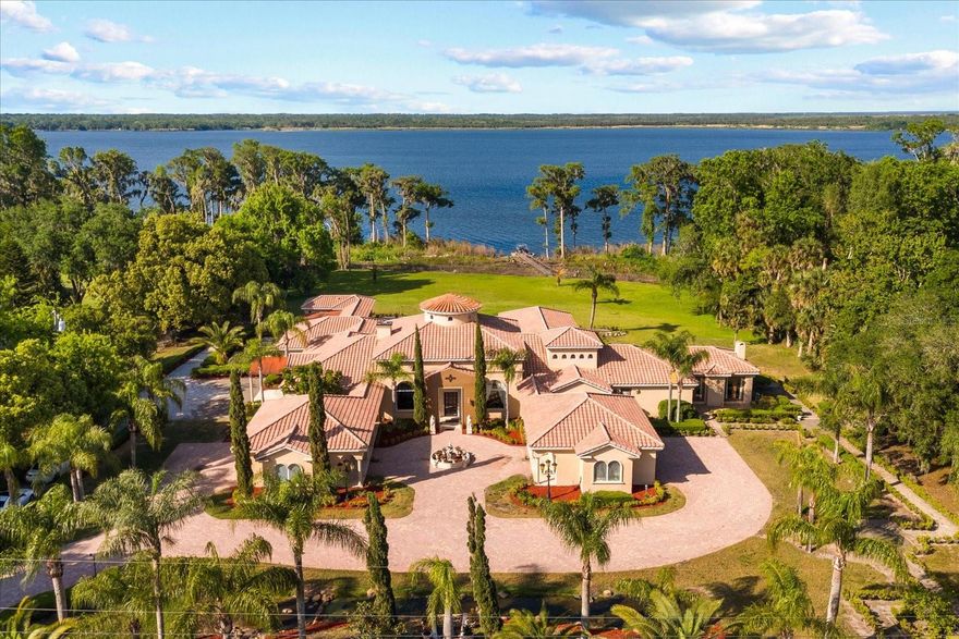 This exquisite lakefront property in Orlando offers a unique blend of luxury and charm, set on a generous 5.33-acre lot without HOA restrictions. The residence features an Italian-inspired exterior, complete with a front waterscape and vibrant gardens, creating an enchanting first impression. Upon entering, guests are welcomed by a grand foyer adorned with elegant marble details and a stunning 24 karat custom-painted dome.

The expansive living area is designed for both comfort and elegance, featuring a grand marble fireplace, unique chandeliers, and panoramic views of Lake Jessup and the inviting pool. The thoughtfully designed "H" floor plan includes over 8,000 square feet of air-conditioned living space, with 5 spacious bedrooms and 6.5 bathrooms all conveniently located on one level.

The primary retreat serves as a sanctuary, boasting 8 sets of French doors that open to the pool and lake, along with a primary closet designed as a "safe room." The adjacent primary bathroom features a serene garden/spa area for relaxation. Culinary enthusiasts will appreciate the state-of-the-art chef's kitchen, complete with top-of-the-line appliances and a generous walk-in butler's pantry.

Additional highlights of the property include a temperature-controlled wine cellar, a private movie theater, and dedicated nanny's living quarters. The 6-car garage offers ample attic storage for convenience. The outdoor oasis features a sports pool with multiple water features, a summer kitchen, a wet bar, and an additional fireplace under a spacious veranda, all overlooking the serene waters of Lake Jessup.

This property is a true masterpiece, showcasing custom-designed finishes with Tuscan and Greek influences, and represents the epitome of luxury living in a picturesque setting. For those interested, scheduling a private tour is highly recommended to fully appreciate this extraordinary residence.
