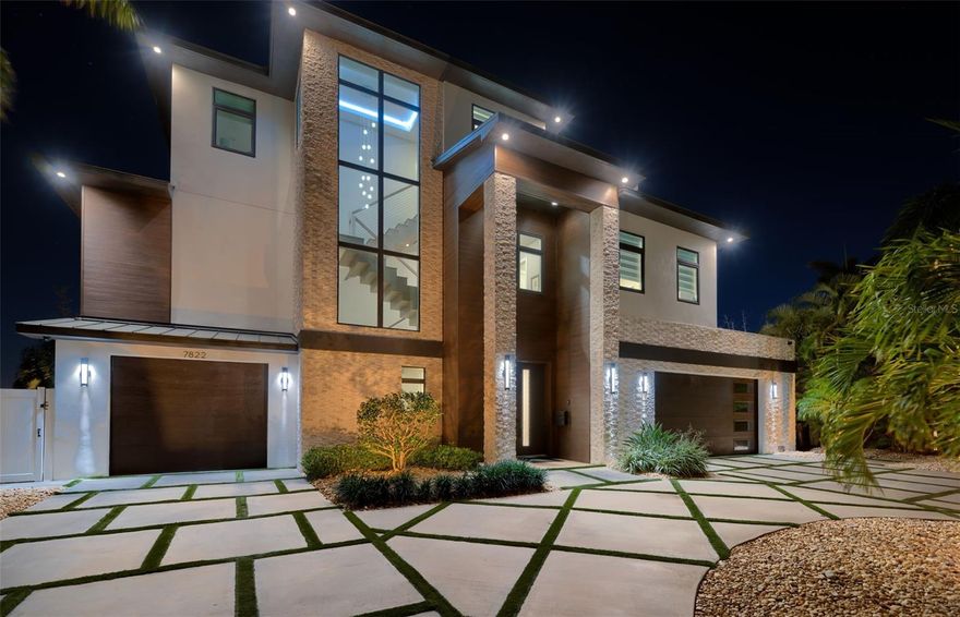 DAZZLING COASTAL CONTEMPORARY ELEGANCE WITH EXCEPTIONAL CUSTOM DESIGNER FINISHES!  Lushly landscaped with a striking curbside appeal, this remarkable waterfront estate residence boasts rich structural symmetry and elite exterior finishes.  Beyond its towering covered entry, discover numerous luxury upgrades, beautiful wood flooring, impressive custom ceilings, radiant lighting and poshly-tailored built-ins.  Step inside the magnificent great room overlooking the waterfront.  Your grand living room area enjoys a bespoke media wall with fireplace, built-in surround sound, and a lovely wet bar with beverage chiller and icemaker.  The sumptuous chef’s kitchen is an eye-catching delight, with double-thick quartz waterfall counters, quartz backsplash, high-quality appliances, a hidden pantry closet, and a huge island bar.  The wonderful open concept dining area overlooks the waterfront.  Step out to the luxurious 250sqft covered waterfront balcony with built-in, tumbled marble media wall/fireplace and gas grilling center.  The resplendent owner’s suite features attractive window treatments, a spacious walk-in closet system and big window views of waterfront.  The plush, inspiring owner’s bath offers two exquisite vanities, a dedicated cosmetics center, impressive herringbone-pattern tilework, a pampering stand-alone soaking tub, and a spectacular glass rainshower enclosure.  You’ll appreciate the large modern office (with designer built-ins) suitable as a den or separate media room.  Upper level includes a fine sitting area and three large bedroom suites (two of which overlook the water) with excellent closet systems and gracefully-appointed with superb finishes.  Lower level has a significant oversized multi-purpose area ideal for storage/fitness/gaming.  Step out back and discover the true definition of outdoor luxury living.  545sqft finished covered deck with exceptional pavers and tumbled marble media/fireplace wall, transitions to a stunning Pebbletec pool with beautifully-tiled 4-sided spill-over spa.  Thick tropical landscaping encloses the backyard area – assuring privacy.  Updated seawall and composite dock support 2 Swinger jetski lifts and a 16,000lb boat lift with catwalk (for accessing both sides of boat).  Incredible laundry facility provides two washers/dryers, beautiful counters and substantial storage.  Fine 3-stop elevator.  Many, many extras.  This is an extraordinary custom waterfront home close to the beaches and less than a 15-minute drive to downtown St. Petersburg.  Dimensions are estimates, buyer to verify.