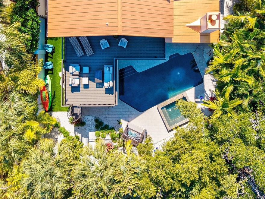 Nestled along a serene canal and embraced by a curtain of mature tropical palms, this custom-remodeled residence unfolds as a private coastal estate—an intimate sanctuary where luxury, tranquility, and effortless island living exist in perfect harmony. Masterfully re-imagined by Eason Builder Group, the home was completely gutted and rebuilt just four years ago, and last year the entire first level was once again fully renovated, resulting in a residence that feels both newly crafted and timelessly refined. From the moment you arrive, a sense of seclusion and calm sets in. As you walk up to the home, an old-growth Gumbo Limbo greets you. Sunlight filters through new hurricane-impact windows, illuminating interiors designed to feel open yet intimate, grand yet soothing. The main living space becomes a natural gathering place, anchored by a custom-built-in entertainment center and a coffee station. An elegant touch that invites slow mornings, refined evenings, and effortless entertaining. Sonos surround sound flows throughout the home, creating an ambient soundtrack for daily life, while a fully integrated security and camera system offers peace of mind and quiet confidence. The kitchen stands as a statement of both beauty and performance, where quartz countertops, solid-wood glass-front cabinetry, a sculptural range hood, designer pendant lighting, and stainless-steel Bosch appliances come together in a space crafted for culinary artistry and connection. It opens seamlessly to the dining area, where a wood-burning travertine stone fireplace adds warmth and architectural presence, setting the stage for candlelit dinners and lingering conversations. Two luxurious primary suites, one on each level offers the rare indulgence of privacy and flexibility. Each is finished with shiplap walls, porcelain tile, recessed lighting, and abundant natural light. The upper-level retreat opens to a private balcony overlooking the pool and tropical grounds, a serene perch for sunrise reflections and evening breezes. Its spa-inspired ensuite features a quartz walk-in shower, while the first-floor primary bath is appointed with a solid-wood double vanity, continuing the home’s narrative of tailored craftsmanship and understated elegance. Completing the residence are two additional bedrooms with a shared bath and an upstairs bonus room ideal for recreation, fitness, or creative pursuits. Beyond the interiors, the estate reveals its most captivating chapter. The backyard unfolds as a secluded resort, where a glistening pool and spa are framed by layered, well-established tropical landscaping that has matured into a living wall of privacy. Covered and open-air lounges invite both sun-drenched afternoons and starlit evenings, while a turf-lined grilling and gathering area provides an elevated setting for alfresco dining. Just beyond the palms, the canal stretches quietly behind the property, creating the illusion that the waterway is an extension of your own grounds and inviting a lifestyle of boating, paddleboarding, and sunset cruises from your private dock. When you venture beyond this sanctuary, the unmistakable charm of Holmes Beach awaits. This is more than a home—it is a refined island retreat, custom crafted for those who seek privacy, comfort, and tranquility, with the rare privilege of a secluded waterfront setting and immediate access to one of Florida’s most cherished beach communities.