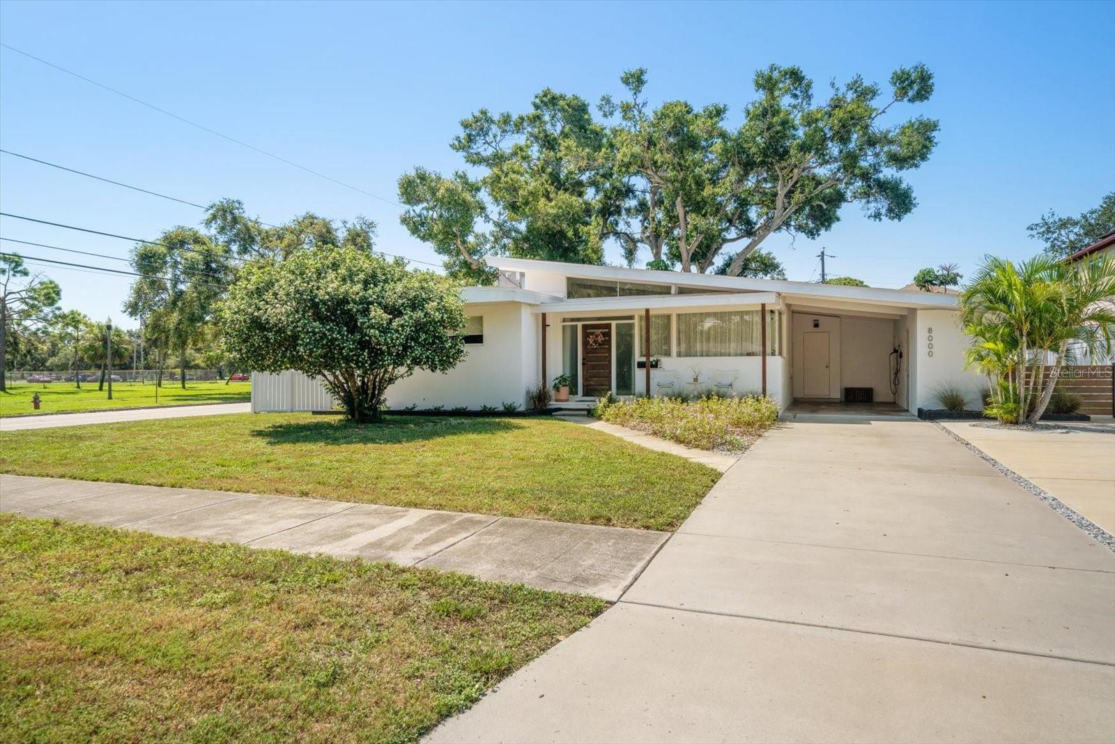 X Flood Zone – High & Dry! This beautifully renovated mid-century modern gem sits proudly on an oversized corner lot (.24 acres) in desirable Jungle Terrace, directly across from the lush greenspace of Walter Fuller Park. Offering 4 bedrooms, two bathrooms and a versatile split floor plan, this home is perfect for today’s lifestyle – one bedroom could easily have its own private entrance, making it ideal as an in-law suite, guest retreat, or home office. Renovated in 2022, the home features bamboo and tile flooring throughout, an updated kitchen and bathrooms, 2022 ductwork & A/C, new appliances (including an induction stove) and a new roof – giving you peace of mind and style all in one. Step outside to enjoy the expansive garden oasis, complete with shady areas, room for a pool, and even a whimsical treehouse. The covered carport includes two oversized storage rooms, perfect for bikes, paddleboards, or gardening tools. Plus, the generous driveway easily accommodates 4+ vehicles. This is the perfect blend of mid-century charm, modern updates, and outdoor living – all in a prime location just steps from one of St. Pete’s most beloved parks.