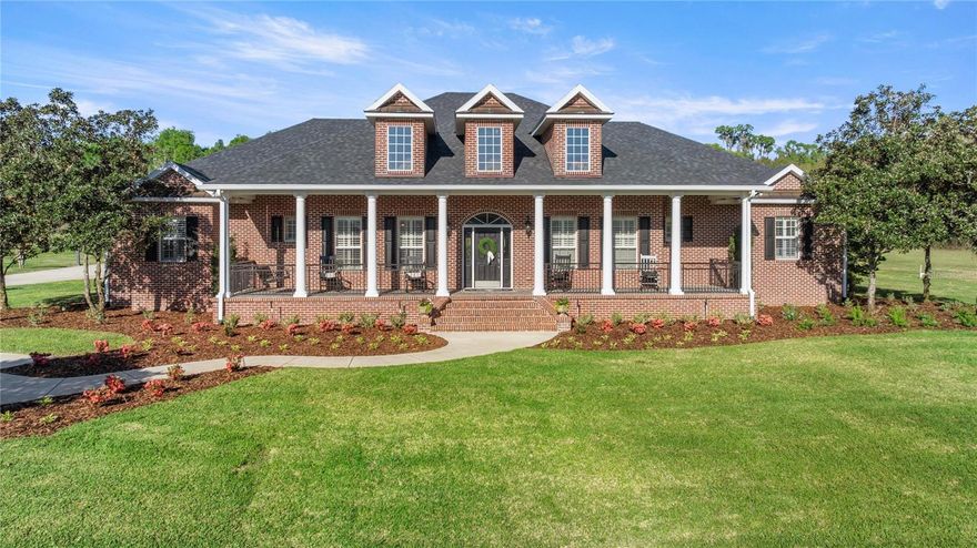 One or more photo(s) has been virtually staged. Located in the private gated community of Whisper Crest in SW Ocala, this all-brick estate home sits on a cleared 4.43 acres. The exterior boasts stately front porch columns, brick paver porches, and all-new professional landscaping. Extensive updates include a new roof, full interior refresh, exterior pressure washing, and much more—making this property truly move-in ready! Spanning a generous 4,158 square feet, the interior is masterfully designed for both comfort and privacy. All four of the spacious bedrooms function as private suites, each boasting full en-suite bathrooms and walk-in closets. The primary suite is oversized with elegant tray ceilings, dual walk-in closets with custom built-in shelving, and a spa-inspired bath complete with dual vanities, a soaking tub and a custom-tiled shower. A conveniently located half-bathroom easily accommodates guests. Continuing with the highly functional layout, the home features a living room, formal dining room, large secondary den, game/media room, and an indoor laundry room, with wood flooring running throughout the main areas. The spacious living room is anchored by a coffered ceiling and a classic brick gas fireplace, while the den offers vaulted wood-beam ceilings and a stone gas fireplace. The kitchen is equipped with granite countertops, professional-grade stainless steel appliances (including a gas stove), a large central island, and a distinctive brick accent wall. Adjoining the kitchen is a sun-drenched breakfast nook with expansive bay windows, alongside the formal dining room detailed with elegant wainscoting. Outdoor living is centered around a swimming pool and raised spa, upgraded with all-new pool equipment in 2026. The space is built for entertaining, featuring an oversized covered lanai with a full outdoor kitchen and a new grill, plus a separate poolside cabana with a built-in bar and a convenient half-bathroom. A stone fire pit sits nearby. Vehicle enthusiasts will appreciate the three-car attached garage with built-in storage, alongside a 900-square-foot detached garage featuring two large roll-up doors to easily accommodate boats or RVs. Additional property features include City of Ocala Fiber Internet, new water heaters, and two propane tanks that service the gas stove, both indoor fireplaces, and the hot tub. The large 4.43-acre lot and A3 zoning allow for up to one horse for each acre and provide ample space to build barns or equestrian facilities. The property is ideally situated for equestrian enthusiasts, located just 4 miles from the Florida Horse Park and 15 miles from the World Equestrian Center.