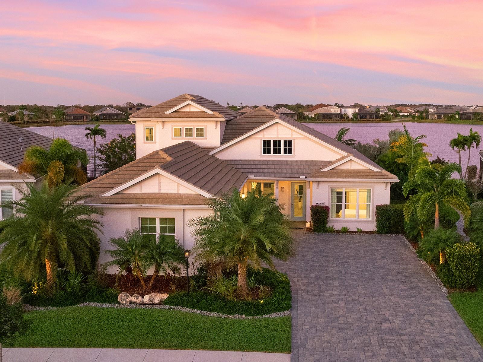 Indulge in the epitome of waterfront opulence with this stunning custom-built coastal residence situated in the exclusive Lakehouse Cove enclave within the esteemed Waterside community. Revel in breathtaking, uninterrupted views of the expansive Lake Mallard, as this exceptional estate seamlessly marries elegance with relaxation. Step inside to explore a luminous and welcoming layout spanning 3,674 square feet, adorned with upscale finishes and designer accents at every turn. The home's grandeur is highlighted by lofty ceilings intricately adorned with custom details. At the heart of the home lies the spacious great room, featuring an electric fireplace flanked by custom built-ins, a striking stone accent wall, and expansive sliders framing panoramic lake vistas, seamlessly leading to the sprawling outdoor lanai. Outdoors, luxuriate in the tranquility of self-cleaning saltwater heated pool or entertain effortlessly in the covered area designed for ultimate relaxation. No detail has been overlooked, with premium amenities including impact windows and doors, and high-volume tray ceilings with intricate detailing. The gourmet kitchen is a chef's dream, boasting top-of-the-line stainless steel appliances, a sizable quartz center island doubling as a breakfast bar, custom wood cabinets with convenient pull-out drawers, and a walk-in pantry for ample storage. Retreat to the extended master suite, offering a serene haven with a sitting area, and a lavish ensuite bathroom complete with dual vanities, a Roman-style shower, and dual walk-in closets. Additionally, a separate office with built-in shelving provides a tranquil workspace with breathtaking water views, conveniently located near the powder room doubling as a pool bath. Upstairs, a spacious bonus/media room awaits, ideal for movie nights or casual gatherings, accompanied by a third bedroom and full bathroom, offering flexibility and convenience for guests or a teen suite. With over $250k in upgrades, including a contemporary fireplace in the great room, porcelain tile plank flooring, all bedrooms are offering walk-in closets with custom built-ins, quartz counter tops, plantation shutters, window coverings, tankless water heater and tray ceilings. No expense has been spared in creating this unparalleled sanctuary. Outside, lush landscaping envelops the property offering a serene and private escape. The home benefits from increased privacy, with no neighboring houses facing the front entrance, and boasts picturesque views of the preserve sanctuary. Discover the pinnacle of waterfront living in this better-than-new home, where every detail has been meticulously crafted to offer the ultimate in luxury and comfort. Waterside community encompasses seven lakes and 20 acres of shoreline, nature preserves and walking trails. Enjoy a variety of shopping and dining options and a water taxi from Lakehouse Cove boat house to Waterside Place Marina. Lakehouse Cove residents have access to a rich-filled amenity center with a resort-style pool, spa, lounging cabanas, fire pits, play area, pickleball courts, bocce ball and a 24-hour fitness center. Meet up with your friends and neighbors in the luxurious clubhouse with fully equipped kitchen, board and meeting room, game room and outdoor verandas. Don't miss this beautiful home in the coastal community of Lakehouse Cove at Waterside in Lakewood Ranch.