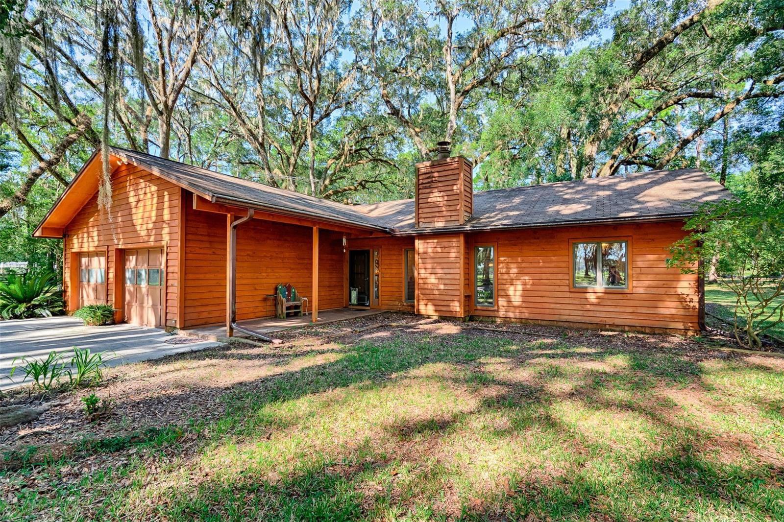Located off a scenic Florida highway this cozy 3 bedroom 2 bath home with a bonus room is on 5.25 acres and tucked away among the majestic oak tress offering a perfect blend of seclusion and convenience. This peaceful woodland retreat offers peace and privacy in the middle of Springs Country and just minutes away from the charming towns of High Springs and Newberry. When you come through the gate and drive through the oak hammock you are greeted with a rough-cut cedar siding home. The interior features a living room with wood burning stone fireplace, engineered wood floors, and a split floor plan. The kitchen is spacious with a large window showing off the picturesque backyard. Sliding glass doors lead to the screened in porch where you can sit and listen to the birds sing their morning songs. The private primary suite features two walk in closets and double vanity bathroom. 2 spare bedrooms and guest bathroom are on the other side of the home. Enjoy the bonus room that has a separate entrance from the porch perfect for your home office, craft room or getaway space. Additional features include a large Pole Barn, storage shed, well, septic, double paned insulated Anderson windows, and completely fenced property with electric entry gate. Nature is plentiful with crystal clear springs, rivers, and nature trails in all directions. Enjoy country living minutes from shopping, restaurants, and excellent schools. Easy commute to the University of Florida, UF Health, VA, and HCA Hospitals. Check out the video and then see it in person. https://listings.swg.media/videos/01992d07-d94c-73b3-bebd-f95ac40e5ccd