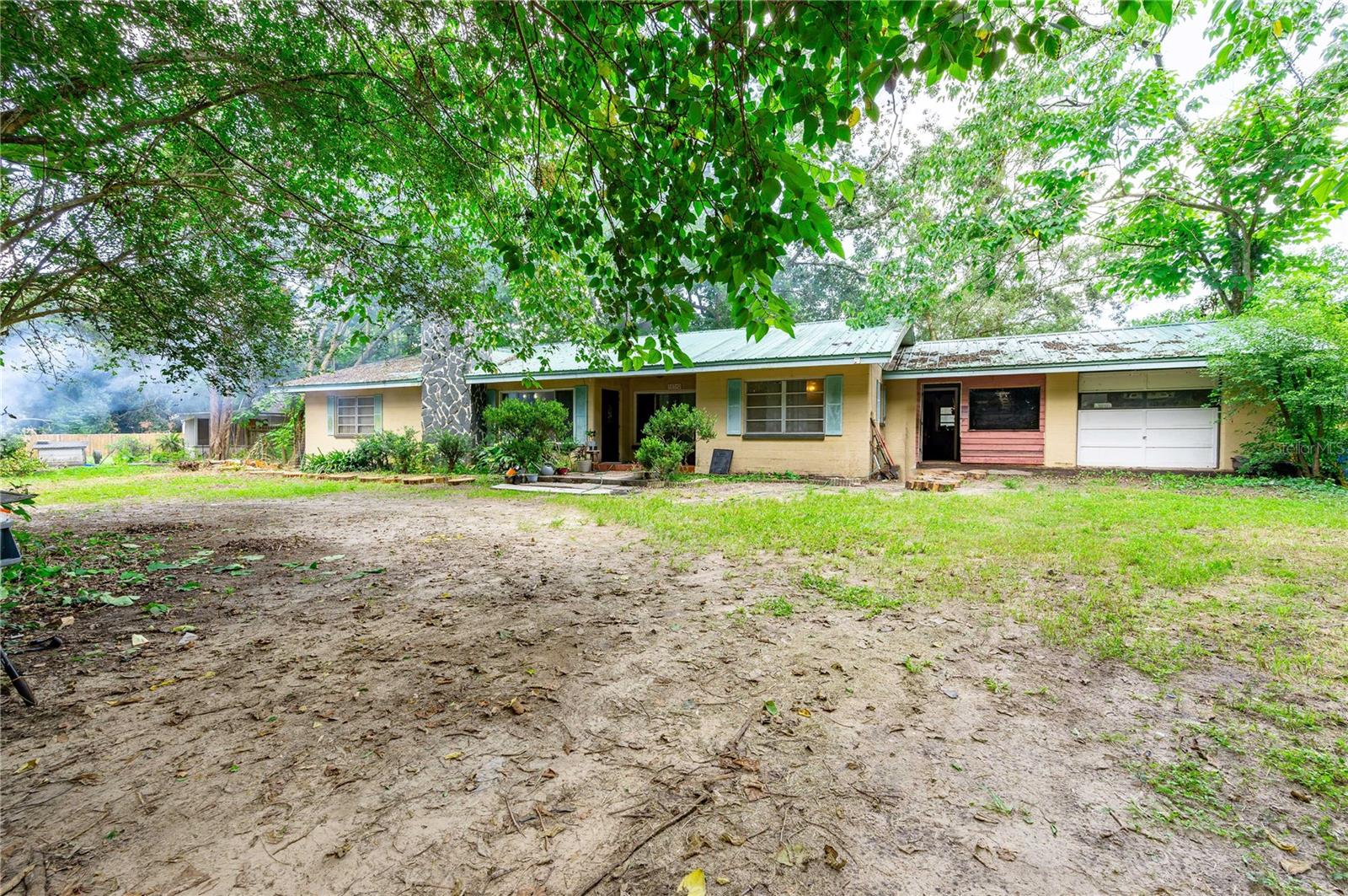 FANTASTIC FIXER-UPPER OPPORTUNITY! Solid concrete block home with metal roof just waiting for the right buyer to bring it to an updated beautiful country setting home! Originally constructed in 1952, this solid 3 bedroom 2 bath (1 bath currently functional, the master bath is rough plumbed out) home features approximately 1,506 sq ft of living area and approximately 2,490 sq ft under roof! Located on a dead end un-paved road the lot is approximately .61 acres and features mature trees and beautiful mature landscaping! The lot is GORGEOUS and semi-secluded! And NO HOA, CDD, or Deed Restrictions! The right buyer can finish up the remodel and vitalization of this great home and property and make it so beautiful! Other features include a wood burning fireplace, oversized approximately 24x26 ft garage with workshop area, huge expansive rear patio area, and circular driveway. Plenty of room to have the pets, small farm animals, and extra vehicles, ATV's, RV, and so much more! Zoned AR and Located in Pasco County jurisdiction for lower county taxes, yet extremely close to shopping, retail, schools, and medical services! Home is not located in a flood zone per Pasco County. Priced low at $225,000 as the new buyer will need to finish the remodel, bring up to current code including electrical work, bathroom plumbing work, new well and septic, and other aesthetic projects. The sale of the property will require approval and an assignment of contract between the existing lease option tenant and the current owner of record. If you are the right buyer, willing to get the work done, this home and fantastic opportunity is for YOU! Call today for your tour! Before this opportunity is gone!