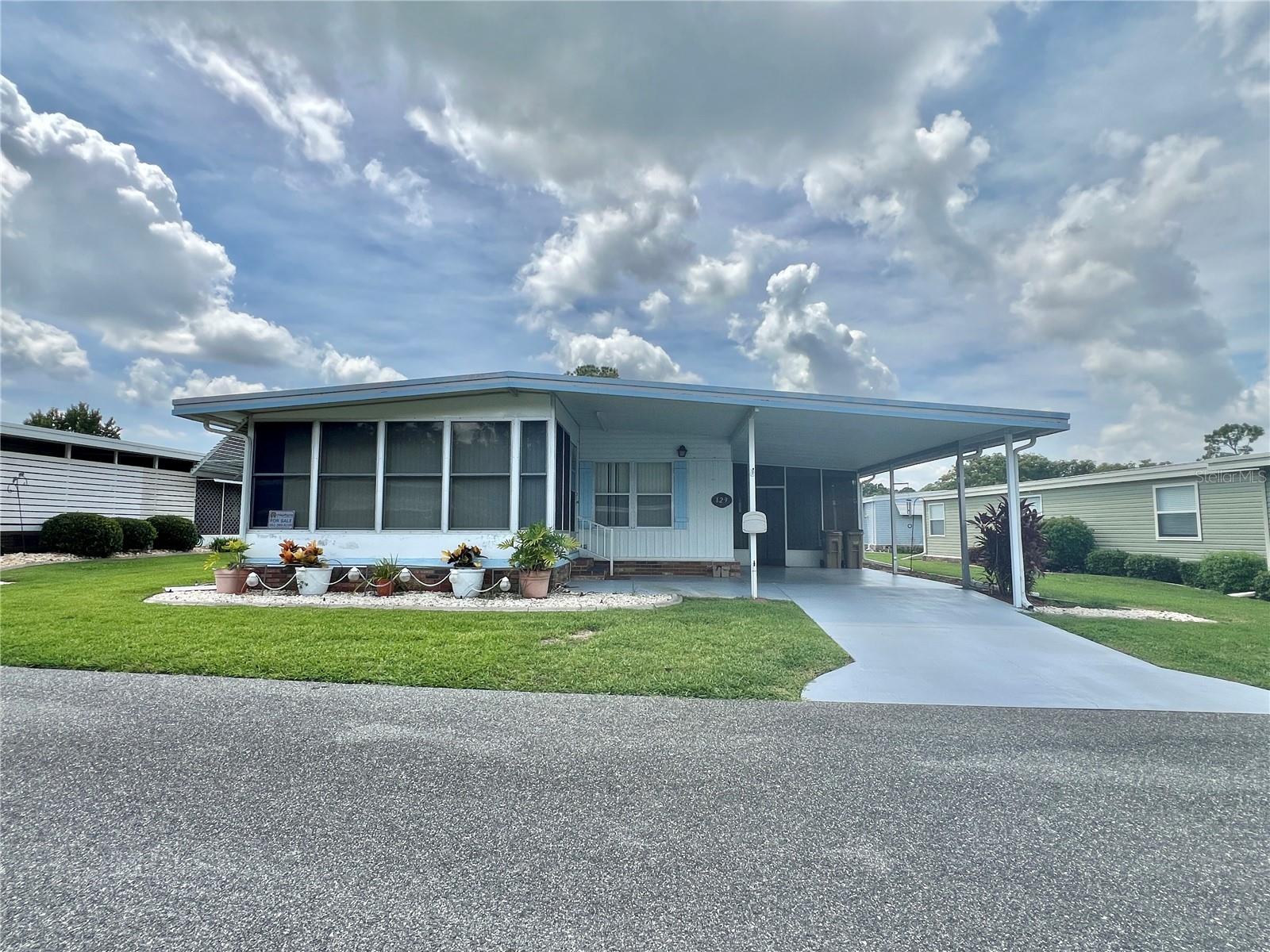 One or more photo(s) has been virtually staged. This beautifully maintained 2-bedroom, 2-bathroom home offers 1,200 sq ft of thoughtfully designed living space, perfect for year-round Florida living. Built in 1978, this residence has been tastefully updated while preserving its welcoming charm. Step inside to a spacious floor plan featuring a Florida room under heat and air, ideal for relaxing or entertaining in comfort. The upgraded kitchen shines with new countertops, a large new sink, fixtures, modern backsplash and appliances, opening seamlessly into the main dining and living areas. New vinyl plank flooring runs through the kitchen and hallway, offering both style and durability. Both bedrooms feature walk-in closets, and the bathrooms include walk-in showers for added convenience. You’ll love the large utility, workshop, and laundry room, complete with a newer washer and dryer, providing ample storage and function. Enjoy Florida’s beautiful weather from the screened side porch or take advantage of the painted, extended driveway, perfect for extra parking or outdoor gatherings. Additional highlights include a new roof (2025), single-ply membrane, HVAC system (2014), spacious layout and natural light throughout. This home offers the perfect blend of comfort, upgrades, and livability. Don’t miss your chance to own this gem on Hibiscus Way!..........Hawthorne at Leesburg is an active, resident owned, 55+ cooperative, waterfront, gated community, with beautifully landscaped grounds, lakes with illuminated fountains and a relaxing and comfortable gazebo. The affordable monthly maintenance fee of $346 includes water, sewer, lawn mowing, private emergency services and storage space for recreational vehicles, boats, trailers and much more! The beautiful clubhouse is complete with a full-time program coordinator, more than 100 different activities and seating for 550. It has a hospitality lounge, card rooms, craft rooms, billiard room, fitness center, library, fine arts room and many more. There is excellent fishing, outdoor geo-thermally heated pool and two enclosed therapeutic pools. Hawthorne boasts a private marina monitored by an electronic security system with over 120 boat slips and access to the Harris Chain of Lakes and beyond.