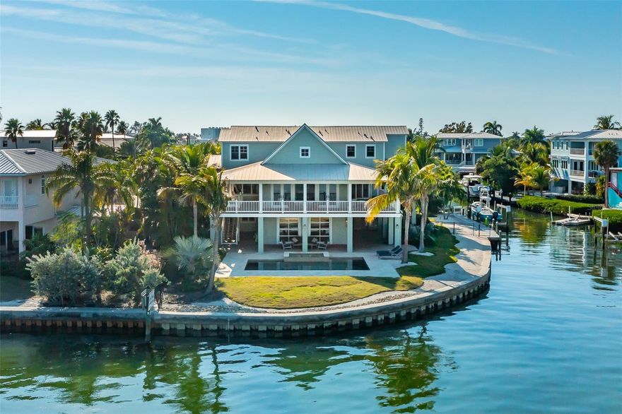 Welcome to this 4,995-square-foot architectural masterpiece designed by well-known architect Gene Aubry, featuring five bedrooms, five baths, an office, a second living area and a gym, all situated on 225 feet of direct bay frontage in Holmes Beach. This Anna Maria Island estate reflects superior craftsmanship and thoughtful detail, from the hand-scraped maple flooring, metal roof, to impact-resistant Anderson windows, new high efficiency air-conditioning units, tankless water heater, an oversized garage with new epoxy flooring, an updated spa-style primary bath and an elevator servicing all levels. The chef's kitchen is equipped with Sub-Zero refrigeration, Wolf and Bosch appliances, a new built-in ice machine, beverage cooler and custom cabinetry ideal for everyday living and elevated entertaining. Additional features include whole-home audio and security systems, a dedicated gym with epoxy flooring and a bonus room pre-plumbed for an efficiency kitchen. Outdoors, professional landscaping with curated lighting surrounds a saltwater pool and spa with all-new equipment. Irrigation is supported by a rain-fed cistern system. A composite wraparound deck that is plumbed for an outdoor kitchen, and a mosquito-control misting system for added comfort while enjoying unobstructed bay views. Boaters will appreciate the newer seawall, 10,000-pound lift and fish cleaning station. This rare waterfront estate presents the opportunity to own a residence that embodies architectural integrity, refined island living and modern luxury.