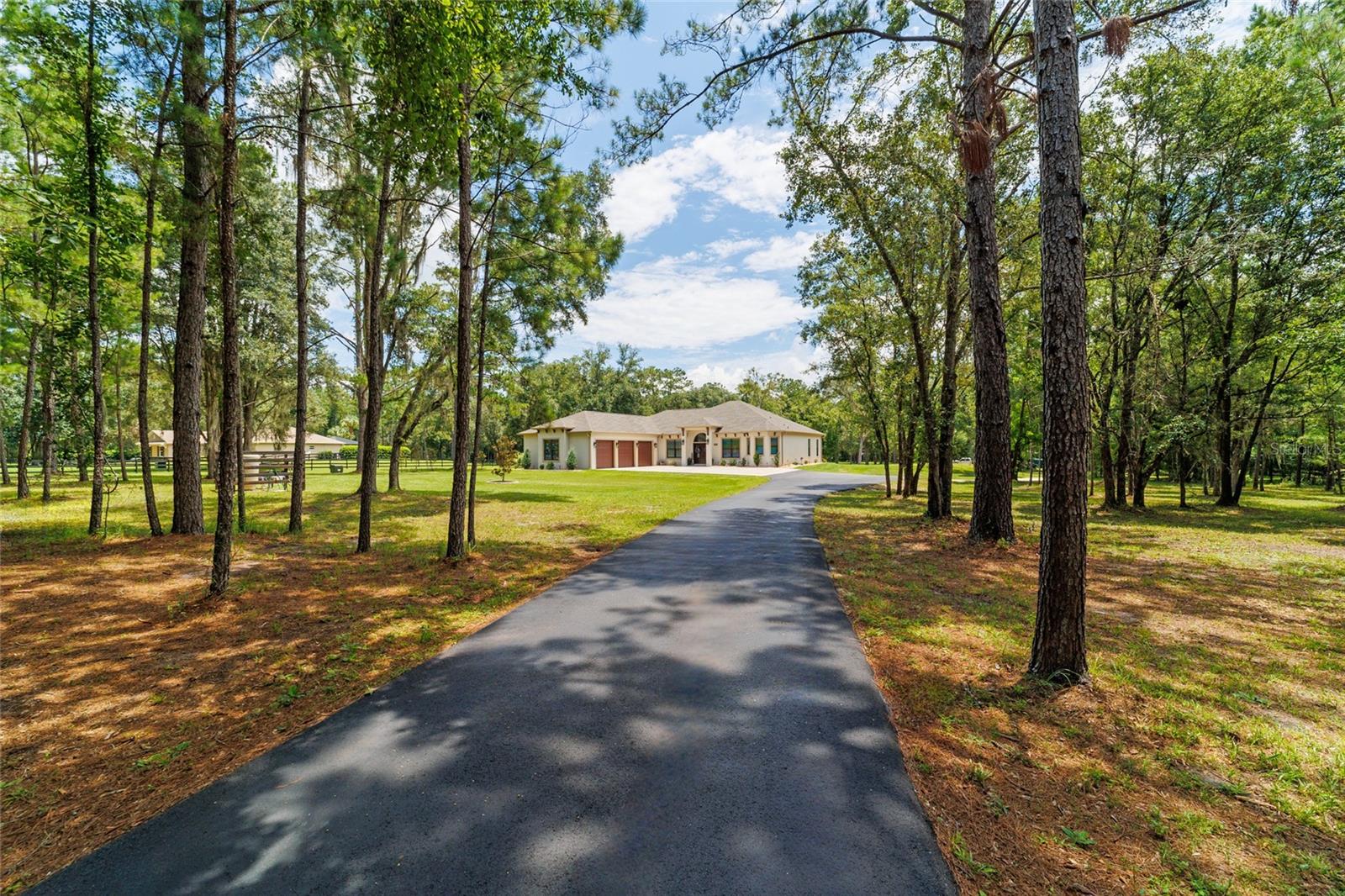 Welcome to this beautifully designed 2022 custom home, nestled on 7.33 private acres in The Village at Hidden Lakes, a gated equestrian community where deer and turkey often wander through the yard and peaceful mornings start with nature right outside your window. This is one of the largest lots in the neighborhood, offering the perfect combination of tranquility, privacy, and potential for your dream farm or country retreat.
As you arrive, an automatic iron gate opens to a winding asphalt driveway, leading you beneath scattered oaks and past lush, green grass to the front entrance. The home is thoughtfully set back on the property, framed by mature trees and beautifully landscaped with river stone accents. Whether you plan to bring horses or simply want room to breathe, this property delivers the lifestyle you’ve been dreaming of.
Step inside and you’ll immediately appreciate the open, inviting floor plan designed for both comfortable living and effortless entertaining. With 2,597 square feet of living space, this home feels bright and airy, thanks to expansive Pella windows that fill the home with natural light. The living room features wood-look tile throughout, and a stunning floor-to-ceiling stacked stone gas fireplace with a remote thermostat, elevated hearth, and custom mantle—perfect for cozy evenings at home. The main living space also includes a dedicated area for your dining room table, allowing for seamless gatherings and family meals.
The chef’s kitchen is a standout, complete with soft-close custom cabinetry, granite countertops, a gas cooktop, stainless steel appliances, and a coffee station with extra cabinetry and counter space. An oversized kitchen bar is perfect for casual breakfasts, while a separate dining nook overlooks the backyard, creating the perfect spot for morning coffee with a view.
A private office with French doors is located just inside the home near the main living area, offering a quiet space to work from home without sacrificing convenience or flow.
The split floor plan provides privacy for family and guests. The master suite is tucked away on one side of the home, featuring double closets and a spa-style bath with dual vanities, a deep modern soaking tub, and a walk-in tiled shower. On the opposite side, two guest bedrooms share a beautifully finished bath.
An additional half bath and a well-appointed laundry room with cabinet and counter space are conveniently located near the 1,006 sq ft 3-car insulated garage, complete with insulated doors for comfort and efficiency. All interior doors are 36” wide, making the home handicap accessible, and 10’ ceilings with 11’ tray accents add a sense of space and light throughout.
French doors lead from the living room to the covered back porch, where you’ll find a ceiling fan and TV hookup—the perfect place to unwind in the evenings while watching the local wildlife. From here, step into the expansive backyard where you can easily add barns or pastures to create your own horse farm, or simply enjoy the serene, park-like setting with scattered oaks and lush grass.
A storage shed is included for yard equipment, and a list of select furniture is available for purchase with the home.
Conveniently located just 20 miles to I-75, 19 miles to the World Equestrian Center, 9 miles to HITS, 7 miles to Williston, 26 miles to Gainesville, and 20 miles to Ocala, this is the perfect blend of luxury living, rural charm, and modern comfort.