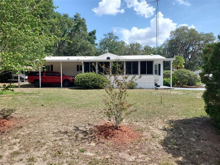 Step into affordable Florida living in this well-cared-for 1998 manufactured home w/ a metal roof on a dead-end street meaning no noisy traffic in front of your home. This 3/2-bedroom home is easy maintenance flooring without carpet, plus three solar tubes that fill the interior with natural light. Situated on its own oversized lot with no HOA, the property includes well and septic for added savings and convenience. Enjoy year-round swimming in the steel-sided 18-foot pool enclosed within a birdcage, allowing you to relax without bothersome bugs or mosquitoes. Dual carports provide ample space for multiple vehicles, boat storage, or recreational equipment. Be prepared for Florida weather with the included Generac generator connected to a buried 250-gallon propane tank. Additional features include RV hookups, saltwater hookup access, and storage sheds with electricity already installed. The open floor plan creates a bright and welcoming living space, while the kitchen features a convenient breakfast bar perfect for casual dining, entertaining guests, or enjoying your morning coffee. Less than 5 miles from the Villages means you have access to enjoy all the shops, restaurants and entertainment that makes this area lively and fun.  Call for your own showing today!