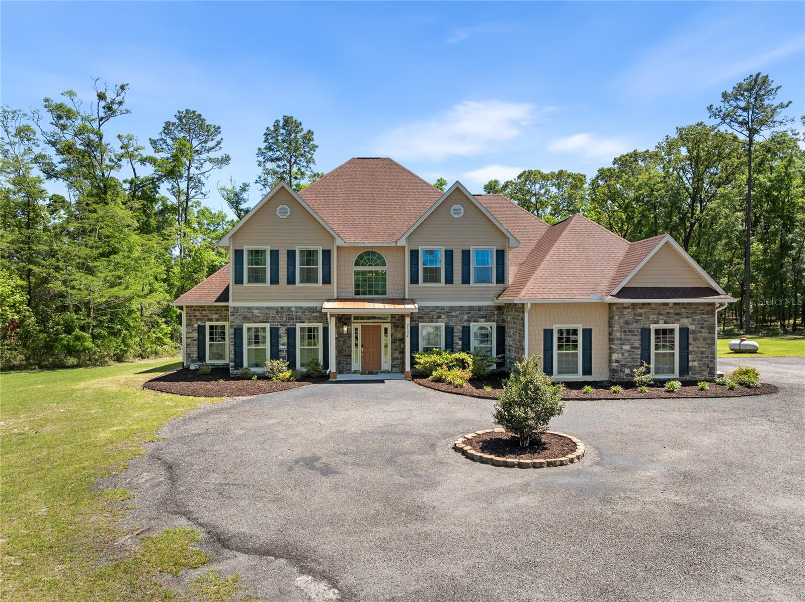 $20,000 Credit towards Buyer's Closing Costs or Buy Down and/or carpet replacement! Tucked within the gated community of Grand Oaks, this luxury 2019-built estate rests on 2.97 beautiful acres, offering the perfect blend of seclusion and accessibility being just 2 miles from I-75. Tree-lined property, towering hardwoods anchor a grand residence, creating a private sanctuary cocooned by nature. The circular driveway will take you this beautiful estate that offers almost 4500 sq ft of heated & cooled spaces and almost 5700 sq ft under roof! The estate has 4 bedrooms with primary suite being downstairs, a second suite upstairs, two other guest rooms adjoined by a shared bath, a large office, a great room, a second living room, an oversized loft, a second office or craft room, a theater room, 3 full baths and 2 half baths! The beautiful foyer with the grand staircase leads you to the great room with cathedral ceilings adorned with wood beams, stone clad statement wall with gas fireplace and gorgeous chandelier! The large office is to the right of the foyer and has artistic built-ins for endless books! The stunning kitchen features beautiful cabinetry, quartz counters, contrasting island, stainless steel appliances (including a gas range), backsplash and tasteful fixtures! The dining room is so spacious and equipped to have host wonderful dinners with friends & family! A cozy coffee station nook is right by the 2nd access to the staircase. Impressive design and lay out! A second living room or den is to the left of the great room! Find the second office or craft room by the laundry! Exceptional planning and design with a lot of love went into building this home. From the back porch, the view unfolds like a living painting- a serene stretch of untouched nature where time slows & peace settles in. Plenty of room for your pool & outdoor living! The primary suite is very very spacious with luxurious en suite bath with garden tub, walk in shower with multiple shower heads, His & Hers closets. The second floor is not to be underrated with its beautiful spaces! Gorgeous wood floors in main areas, handpicked curtains, oversized garage, surround sound, blinds are other features! Welcome home to your luxurious and private oasis! Schedule your private tour today!