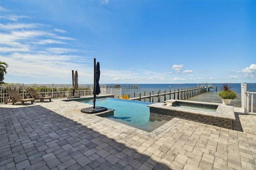 Impressive waterfront property with spectacular sunsets and an unobstructed panoramic view of Tampa Bay, Pine Key, St Pete, downtown Tampa and the beautiful Skyway Bridge. Located in the gated luxury waterfront community of Bay Vista, this custom home is situated on one of best lots in Apollo Beach. The private boat dock features a 16,000# capacity boat lift and three 3,500# jet ski lifts. As you walk towards the front door, you are greeted with grand steps and a cozy front porch. Inside, the foyer with soaring ceilings and a dramatic wooden staircase welcome you home. Just off the foyer is a office/den (ideal home office) as well as a bedroom with ensuite bath. The gourmet kitchen features designer finishes including quartz counters, upgraded stainless appliances, huge breakfast bar, and a large walk-in pantry. The kitchen opens to the spacious great room with sliders and 2-story windows with incredible Bay scenery! The Infinity-edge pool/spa view is breathtaking! The Master suite is upstairs and features a tray ceiling with crown moulding  with an impressive Bay-front balcony! The master bath offers a large shower, jetted tub, dual vanity, and make-up vanity. The secondary bedrooms are large, comfortable and each have access to a private balcony. The stunning heart of this home is the outdoor living with some of the most amazing views of Tampa Bay and the St Pete and Tampa skylines. Perfect for entertaining as the deck has stairs leading to a shelled beach area as well as stairs leading down into the water for swimming. Built with ICF construction (Insulated Concrete Forms) and impact windows to mean insurance expenses are much lower. This property is ideally located near shoppes, restaurants, and major highways.