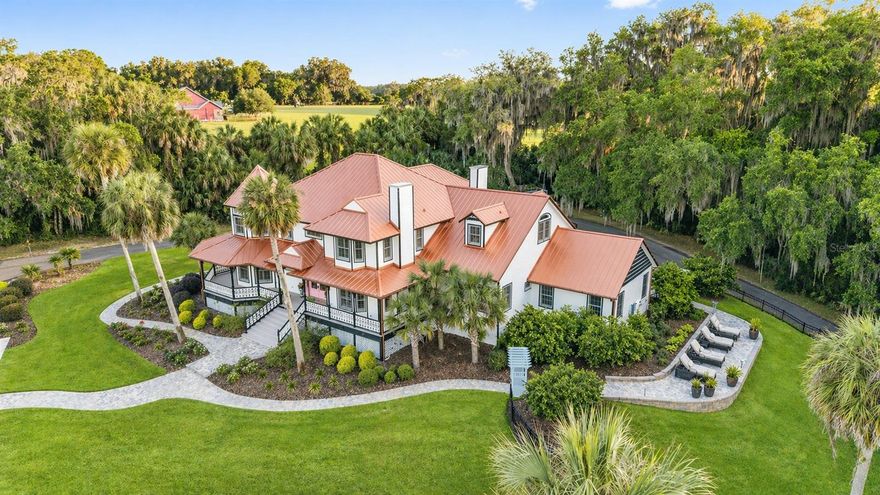 Experience a blend of Southern charm and modern living in Marion County, between Ocala and Gainesville. This gated 22± acre property provides privacy and convenience, featuring two coded entrances and no HOA fees. Elevated on a hill, the home offers stunning views of lush paddocks, the barn and beautifully landscaped grounds framed by mature live oaks. The main residence features four spacious bedrooms, including a first-floor primary en suite with a private study and fireplace, creating a quiet retreat. French doors open to a wraparound porch designed for everyday living and entertaining. Upstairs, three additional en-suite bedrooms offer large closets, spacious baths and abundant natural light through Andersen double-hung windows with plantation shutters. The kitchen has been thoughtfully updated with custom cabinetry, leathered granite countertops and high-end appliances, including an ILVE range and Sub-Zero refrigeration. The home also includes a four-car attached garage equipped with Tesla Powerwall's and an EV charging plug. One notable feature of this property is a separate updated two-bedroom guest house, which includes granite countertops, an open-concept living area, a stackable washer and dryer, and a screened-in pool area that overlooks a fenced pasture. This space is ideal for a family compound, visiting guests or as a rental opportunity. Equestrian amenities are on north end of the property, featuring a four-stall barn with foaling stalls, a large tack and feed room, electric, water and fly system, along with easy turnout to the paddocks. A detached three-car garage/workshop with a full bath offers additional space ideal for car collectors, equipment storage or recreational use. Outdoor living has been intentionally enhanced throughout the property. The pond has been restored and revitalized into a peaceful focal point, featuring a terrace that overlooks the water and grazing horses, creating a relaxed morning and gatherings with friends and family. A cocktail pool and spa add a layer of comfort, while paver pathways and curated landscaping create a natural flow across the grounds. Additional improvements throughout the property support functionality and upkeep, including solar power, new fencing and infrastructure. Minutes from Majestic Oaks Ocala equine facility, Iron Crest Golf Country Club and historic Micanopy, the property is approximately 12 miles to University of Florida and UF Health Shands Hospital, and about 20 miles to the World Equestrian Center.