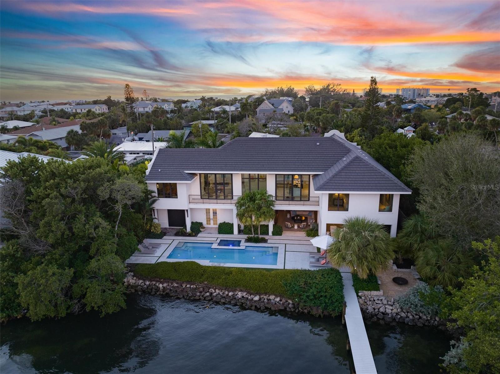 Welcome to your luxury Bayfront paradise! This stunning property offers the ultimate blend of luxury, serenity, and natural beauty with British West Indies vibes. Nestled at the end of a quiet street, the home boasts breathtaking panoramic views Tampa Bay from every angle. Featuring 4 bedrooms and 5 bathrooms there is an abundance amount of space for everyone. Beyond exquisite entry doors, a grand foyer welcomes you into somewhere very special. Step onto the meticulously landscaped grounds, designed by 2022 HGTV award winner, Landscape Architect, Craig Reynolds, the outdoors provides the ultimate private outdoor experience. Your oasis awaits with an expansive first level 1,325 Sq Ft stone patio surrounding a sparkling bay-side heated pool with spa, outdoor fire-pit, mosquito mist system, indoor/outdoor Sonos system, built-in gas barbecue grill with custom stone bar, lounge with handmade paneled TV wall. All the exterior woodwork is Cypress, which is rot free. Enjoy breathtaking water vistas affording the ultimate outdoor pleasure. Perfect for entertaining or simply unwinding as you listen to the gentle lapping of the waves against your private shoreline. Host fabulous cocktail hours, barbecues and pool parties; lounge with a coffee and newspaper in the shade in the covered lounge; or savor the serenity from the upper level deck overlooking the bay. The architectural design of this home is nothing short of spectacular. With 15-foot vaulted ceilings, unmatched millwork, shell reef tile floors, 10-foot doors throughout, and very detailed finishes throughout. Open the expansive impact slider doors to allow an abundance of natural light and experience a true indoor-outdoor experience with Bay breezes. The gourmet kitchen features top-of-the-line Thermadore appliances, 6- burner gas stove, large waterfall island, and a walk-in butler’s pantry with a wine fridge that makes entertaining a breeze. The primary suite is a true retreat with unobstructed sunrise and water views every morning to wake up to. With a connecting custom-built walk-in closet with adjacent bathroom suite with walk-in shower and water closet. There are blackout motorized shades for your utmost privacy. The other 3 well-appointed bedrooms all having their own ensuite bathrooms. Beautifully designed outdoor shower offers an escape from reality, while the connecting dock provides the option for fishing or paddle boarding from your backyard, or jumping onto your boat from the 10,000 lbs lift for a sunset cruise. Attached is a 2-car garage and plenty more parking available in the driveway. There’s a recovery room/ 2nd garage with a custom made cold plunge, the room has an electric rollup screen that allows you to be in the tub and watch the sunrise over Anna Maria sound every morning. The room is also wired for a sauna. Located in the heart of Holmes Beach on Anna Maria Island, you are 2 blocks away from the Gulf of Mexico beaches, shopping at the best boutiques and dining at many restaurants close by. Newsweek released their 25 Most Popular Beach Towns in America, and Anna Maria Island Florida took the top spot. Come see it for yourself and schedule your private showing today!