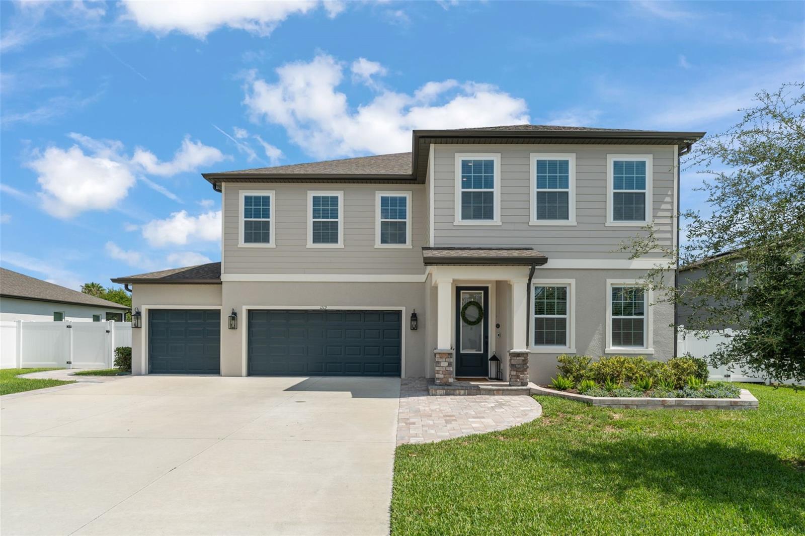 **This property qualifies for a closing cost credit up to $8,900 through the Seller’s preferred lender.** Welcome to 1112 Pearl Tree Rd, a stunning showcase of modern luxury nestled in the beautiful Hampton Oaks community of Deltona, FL. This meticulously designed 4-bedroom, 3.5-bath home offers over 3,700 square feet of thoughtfully curated living space and exudes elegance, comfort, and functionality at every turn. From the moment you enter, you’re welcomed by soaring ceilings, modern light fixtures throughout, and an open-concept floor plan that perfectly balances style and space. The chef’s kitchen is a true masterpiece featuring an oversized quartz island, 42" cabinets with crown molding, stainless steel appliances, a water softening system with an alkaline filter at the faucet, and a dry bar connecting the kitchen to the formal dining room—ideal for entertaining. The formal dining room features floating, lit display shelves, adding an upscale architectural element to the space. The great room is bathed in natural light through six large windows, creating a warm and inviting atmosphere. Gold faucets and finishes are carried throughout the home, adding a sophisticated, designer touch. The home also includes a dedicated office complete with a stunning wall-to-wall built-in bookshelf—perfect for working remotely or a private study space. Upstairs, the luxurious primary suite offers a true retreat with striking accent walls, custom wall trim, and an electric fireplace that adds ambiance and charm. The spa-like primary bathroom includes an extra-large walk-in shower, dual vanities with separate mirrors, a spacious countertop, and a custom walk-in closet with built-in shelving and drawers for elegant organization. Upstairs you'll find the remaining 3 guest bedrooms with one of them featuring an ensuite bathroom. Additional highlights include a stylish laundry room with built-in overhead cabinets, side shelving, and a colorful backsplash that brings a pop of joy to everyday chores. The three-car garage has been upgraded with epoxy flake flooring and currently serves as a gym, complete with mirrors, custom overhead lighting, and a mini split AC for comfort. The screened-in patio opens to an extended paver patio in the backyard, all enclosed by vinyl fencing for added privacy—perfect for outdoor dining, entertaining, or relaxing in your own private oasis. This exceptional property combines top-tier finishes with thoughtful design and a premier location just minutes from I-4, offering quick access to Orlando, beaches, dining, shopping, and more. 1112 Pearl Tree Rd is more than a home—it’s a lifestyle. Schedule your private showing today and experience the very best in upscale Central Florida living.