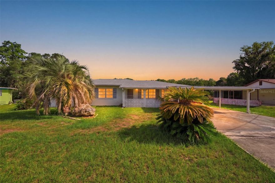 Set along the peaceful shoreline of Tsala Apopka Lake, this classic Florida ranch-style home on a 0.33-acre homesite offers a relaxed waterfront lifestyle with 3 bedrooms, 2 bathrooms, a 2-car garage, and two additional carport parking areas. From the moment you step inside, the foyer opens into a spacious living room where glossy tile-look epoxy flooring flows throughout the home, reflecting natural light from the front-facing window and creating a bright, open atmosphere. At the center of the layout, the dining area connects comfortably to the surrounding living spaces, while just beyond, the family room becomes a standout gathering space with multiple wide windows framing peaceful backyard and lake views. A door from the family room leads directly into the Florida room and patio area, creating a natural transition between indoor comfort and outdoor scenery. Positioned to the left of the dining area, the kitchen features all-white cabinetry, matching white appliances, solid surface countertops, a breakfast bar for casual seating, and a dual sink placed beneath a window overlooking the lake, allowing everyday tasks to feel connected to the water views outside. Located toward the front of the home, the primary bedroom continues the same epoxy flooring and includes a separate single-sink vanity area adjacent to the private en suite bathroom. The en suite bath adds character with a wood-paneled ceiling, beadboard wall detailing, pedestal sink, toilet area, and a step-in shower. Bedroom 2 offers a spacious built-in closet, matching flooring, and a window that brings in natural light, while the nearby guest bathroom features extended single vanity space, white storage cabinetry, decorative half-wall tile accents, a window near the toilet area, and a step-in shower with sliding glass doors. Bedroom 3 provides even more space with dual closets and a front-facing window that brightens the room throughout the day. A mud room with corridor access to the garage adds everyday convenience and functionality. Toward the rear of the home, the fully enclosed Florida room is surrounded by a wall of windows that showcase beautiful lake views and create a relaxing space to unwind year-round, while a door opens onto the elevated deck patio where you can enjoy peaceful mornings, sunsets over the water, or evenings spent outdoors surrounded by the natural beauty of the lakefront setting. Located in Inverness, this waterfront property is close to Fort Cooper State Park, known for its scenic trails, lake access, and natural landscapes; the Withlacoochee State Trail, offering miles of biking and walking paths through Florida’s nature preserves; and Downtown Inverness, where local dining, shops, parks, and community events create a charming small-town atmosphere with convenient access to everyday amenities.