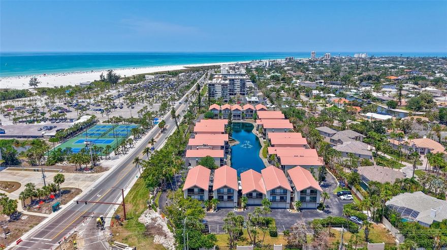 Professionally Redesigned, Renovated & Updated in 2021, this lake-front Contemporary Coastal Chic townhouse is sure to delight! Located just steps away from the cool quartz sand on Siesta Key Beach this open, light & bright townhouse lives large with high ceilings & 4 sets of glass sliders. This 2-bedroom, 2-full bathroom home has a 1-car garage under the unit with extra storage space for the equipment to enjoy sand, pool & tennis/pickleball activities. Start your day with coffee & sunrise on the Eastern balcony & wind down on the 21 ft. covered porch with long-lake views & sunsets over the Gulf! The remodeled kitchen with soft-close hardwood cabinets, Quartz Countertops, & detailed tile backsplash is well equipped for efficiency to serve the adjacent dining table or kitchen dinette.  The Primary Ensuite has a long-lake view from the King bed & large screen TV. The spa-like Ensuite has a solid-wood double vanity w/ Quartz top, detailed porcelain flooring, a walk-in shower w/ Frameless Glass Enclosure & 2 large closets. Bedroom #2 is separated on the 2nd floor, has 2 twin beds & enjoys the morning Sunrise over the balcony. The 2nd full bathroom, also on the 2nd floor has an enlarged tub, dual showerheads, folding glass shower curtain & solid wood single vanity w/Quartz top. The solid-surface floors throughout & the full-sized in-house washer & dryer provide easy maintenance. Onsite amenities include tennis, a resort-style pool, BBQ & picnic area.  Across the street, the Siesta Key Public Beach offers Pickleball, Tennis, a Kid’s Playground, Lifeguards, wheelchair access & Sand Volleyball on the beach. A FREE Trolley runs up & down the Key to a variety of restaurants, bars, small boutiques & shops. Being sold turn key, this is a wonderful opportunity for a new owner and/or also a great investment property. The owners currently have the home in an Airbnb and there is also an onsite, short-term Rental Company with a waiting list for 2026 reservations. Siesta Key Beach was Ranked in 2025 by Tripadvisor #1 beach in the U.S. & #4 in the world. The Townhomes at Our House on The Beach do not last long on the market, so don’t miss your opportunity!