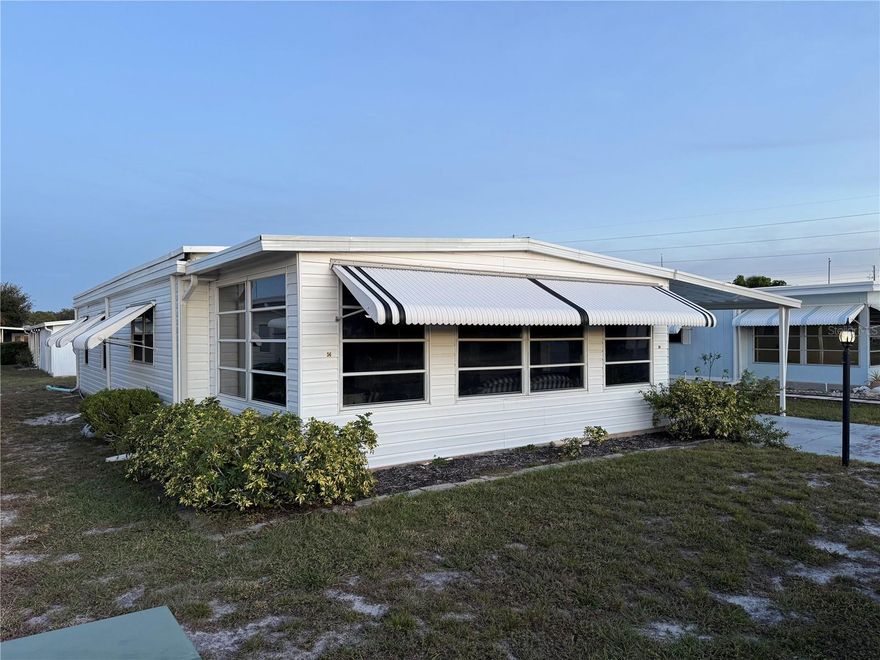 Discover this move-in ready 2-bedroom, 2-bath home with a 1-car carport and utility room, located in the desirable 55+ community of Lake-N-Golf on the beautiful shores of Lake Henry. This well-cared-for home offers a bright, open floor plan featuring a fully equipped kitchen, spacious living and dining areas, and a lovely Florida room—ideal for entertaining or relaxing. The primary suite includes an en suite bath and walk-in closet, while the guest bedroom and bath provide comfortable accommodations. The utility room offers extra storage, and the home is being sold completely furnished! Enjoy resort-style living close to shopping, dining, medical offices, and just minutes from the interstate, Disney parks, and international airports. Experience comfort, convenience, and community—schedule your private showing today!