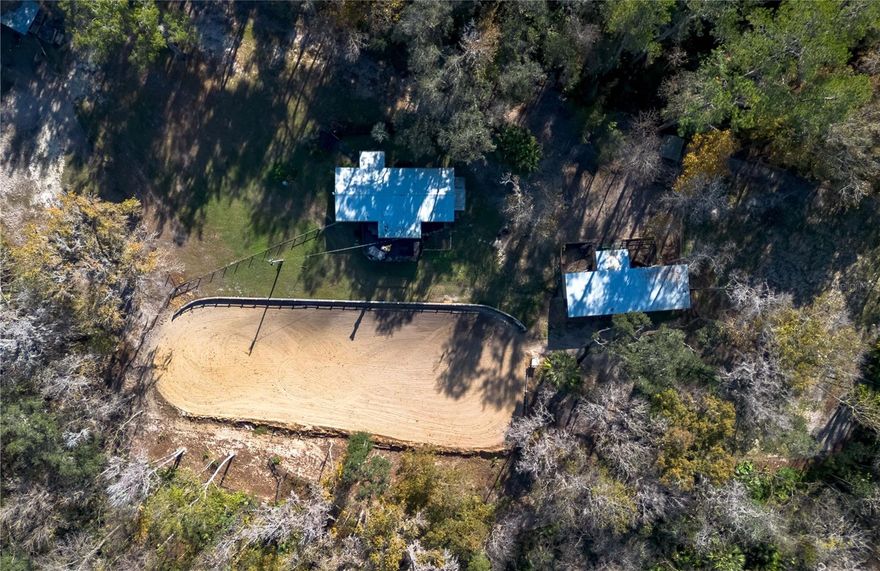 High and dry on 3.22 acres of rolling land, this thoughtfully designed small-acreage farm offers an ideal opportunity for an equestrian looking for a private, natural setting. Fenced and gated, this farm thoughtfully designed for ease of training and maintenance. At the heart of the property is the professionally designed 22x50m riding arena, ideal for schooling and groundwork, and flanked by three fenced pastures. Two barns are established on the property– a 2-stall barn with wash rack and tack/feed stall, and a 3-stall shedrow-style barn with wash rack and additional feed/tack stall. A 50-amp RV hook-up provides flexibility for guests, short-term stays, or future expansion. Whether you’re a serious rider or simply seeking a peaceful place to call home, this property delivers on both form and function. The residence is a completely remodeled 3-bedroom, 2-bath manufactured home that offers over 1,300 sqft of space. Inside, modern updates include luxury vinyl flooring, updated features, lots of natural light, and a split-bedroom floor plan that ensures plenty of privacy throughout. The kitchen is equipped with plenty of cabinet and counter space, stainless steel appliances,  tiled backsplash and countertops, additional pantry storage, and a breakfast bar. Each bedroom is warm and inviting, but the primary suite is the true standout with a spacious layout and a private en-suite that features a garden tub and separate glass-door shower. To the back of the home is a screen-enclosed lanai and an elevated deck, perfect for year-round outdoor enjoyment under the shade of mature trees. The deck directly overlooks the arena, allowing students or trainers to view the rider and horse from a better vantage point. Additional features of note include a kennel/dog run, multiple storage sheds, and a hot tub for post-ride relaxation. Zoned A-1 and situated on a quiet, dead-end road, the setting offers the perfect blend of seclusion and convenience. Located just 5 minutes on foot to the heart of charming Micanopy and just a short drive to both Gainesville and Ocala, this property provides the perfect blend of countryside living and everyday convenience!