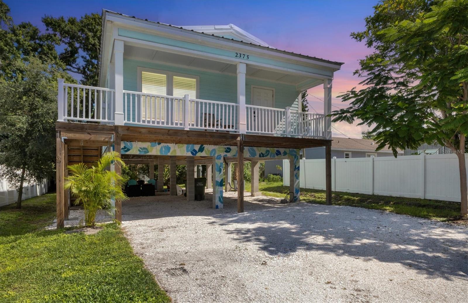 Elevate your lifestyle in this unique island-style home in the heart of Sarasota! An exceptional opportunity to experience the best of Florida living and an effortless move-in with all turnkey furnishings included, allowing you to settle in immediately. The interior is bright, optimized, and beautifully finished with luxury vinyl floors, shaker style cabinets, smooth finish doors, and smart TVs throughout, creating a modern and inviting atmosphere. The spacious living room and alcove with an antique bar cart and desk are adjacent to the dining area and a fully equipped kitchen, featuring elegant stone countertops and "smart" Samsung stainless steel appliances—ideal for entertaining guests or enjoying family meals. For your convenience, the interior laundry area includes a Samsung washer and dryer. This delightful home, built in 2022 to current building codes, ensures peace of mind with optimal construction features including impact windows, durable metal roof, and elevated stilt-on-concrete-piling construction with ample under-building carport style parking for two cars. With three bedrooms and two full baths, it comfortably sleeps eight, making this home perfect for families or groups. Located in a coveted area between vibrant downtown Sarasota and gorgeous Gulf Coast beaches, you can easily walk to Arlington Park and Aquatic Complex, head to Lido Key Beach or world-famous Siesta Key Beach with its quartz crystal sand, or simply relax in the serene, tree-lined backyard. This home is currently used as a part-time vacation home and for weekly vacation rentals. It's ideal as a full-time residence, a convenient part-time vacation home, or for continued weekly rentals, offering flexible ownership options. You will also love the close proximity to Sarasota's vibrant arts and culture scene, diverse dining venues, Sunday Farmers Market, the stunning Sarasota Bayfront and marina, and abundant recreational activities.