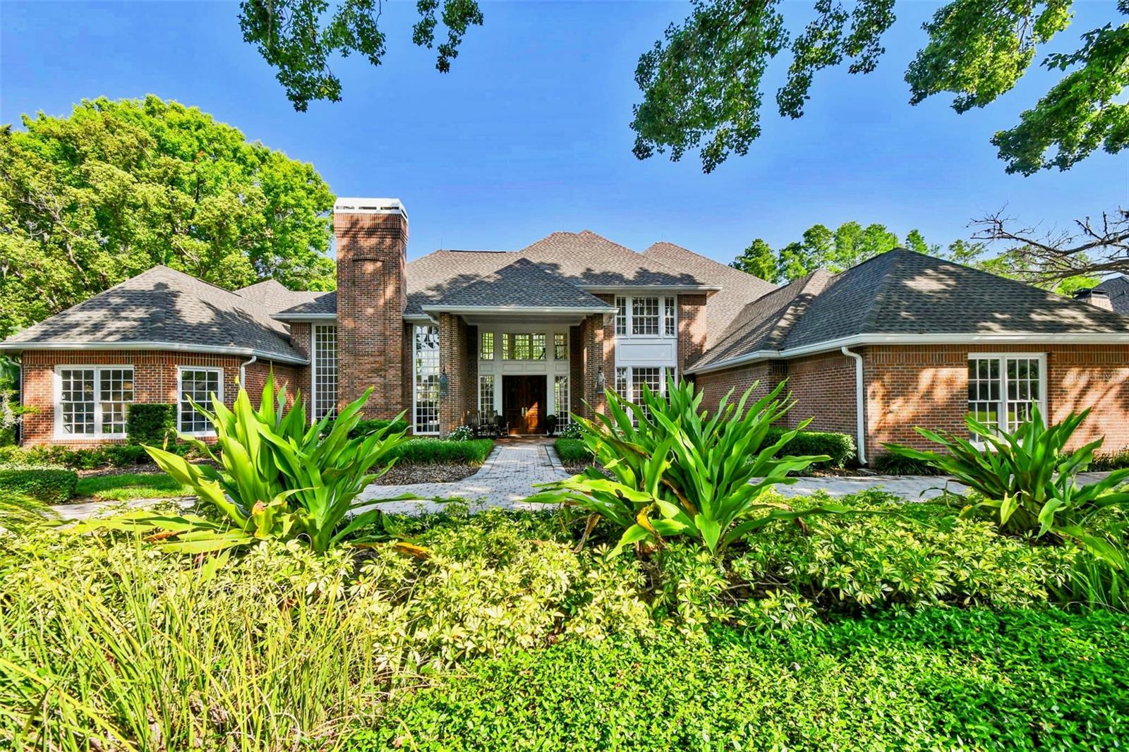 Discover this exceptional opportunity to lease this stunning brick estate, perfectly positioned in the heart of Avila, Tampa Bay’s premier guard-gated golf and country club community. Renowned for its luxurious lifestyle and unparalleled amenities, Avila offers an amazing living experience. Set against a backdrop of beautifully landscaped grounds and sweeping golf course views, this magnificent residence features 5 bedrooms, 5.5 bathrooms, and an impressive array of refined living spaces. Upon entering, you are greeted by a dramatic two-story foyer, highlighted by a custom-built, winding staircase framed by floor-to-ceiling windows that reveal breathtaking vistas of the pool and golf course.
The living room exudes sophistication, with rich wood floors, wood-paneled walls, a coffered ceiling, a wood-burning fireplace, and expansive windows that bask the home in natural light. The open floor plan seamlessly blends indoor and outdoor living, creating an ideal setting for both entertaining and intimate gatherings. The formal dining room is elegantly appointed with crown molding and decorative lighting, while the gourmet kitchen, includes double ovens, a warming drawer, a Sub-Zero refrigerator, and a cozy breakfast nook. Adjacent to the kitchen, the family room features a fireplace and an adjoining custom bar with a beverage refrigerator and wine cooler—perfect for hosting guests. The sunlit sunroom serves as a peaceful retreat, offering relaxation and comfort year-round. The luxurious downstairs primary suite is a private haven, thoughtfully designed with dual bedrooms for ultimate privacy, a formal office, a fitness room and a beautiful en-suite bath featuring dual sinks, separate water closets, spacious walk-in closets, and a serene sitting area that could serve as an additional bedroom, nursery, or personal office. Upstairs, three spacious en-suite bedrooms provide comfort and privacy, with two rooms opening onto a terrace that overlooks the sparkling pool, lush gardens, and golf course. The outdoor living area is truly an oasis, featuring a shimmering swimming pool, spa, and an expansive patio perfect for soaking in the Florida sunshine. This extraordinary residence harmonizes classic elegance with modern luxury, offering a lifestyle beyond compare. Experience the unparalleled charm and sophistication of Avila—Tampa’s most beautiful and sought-after community.