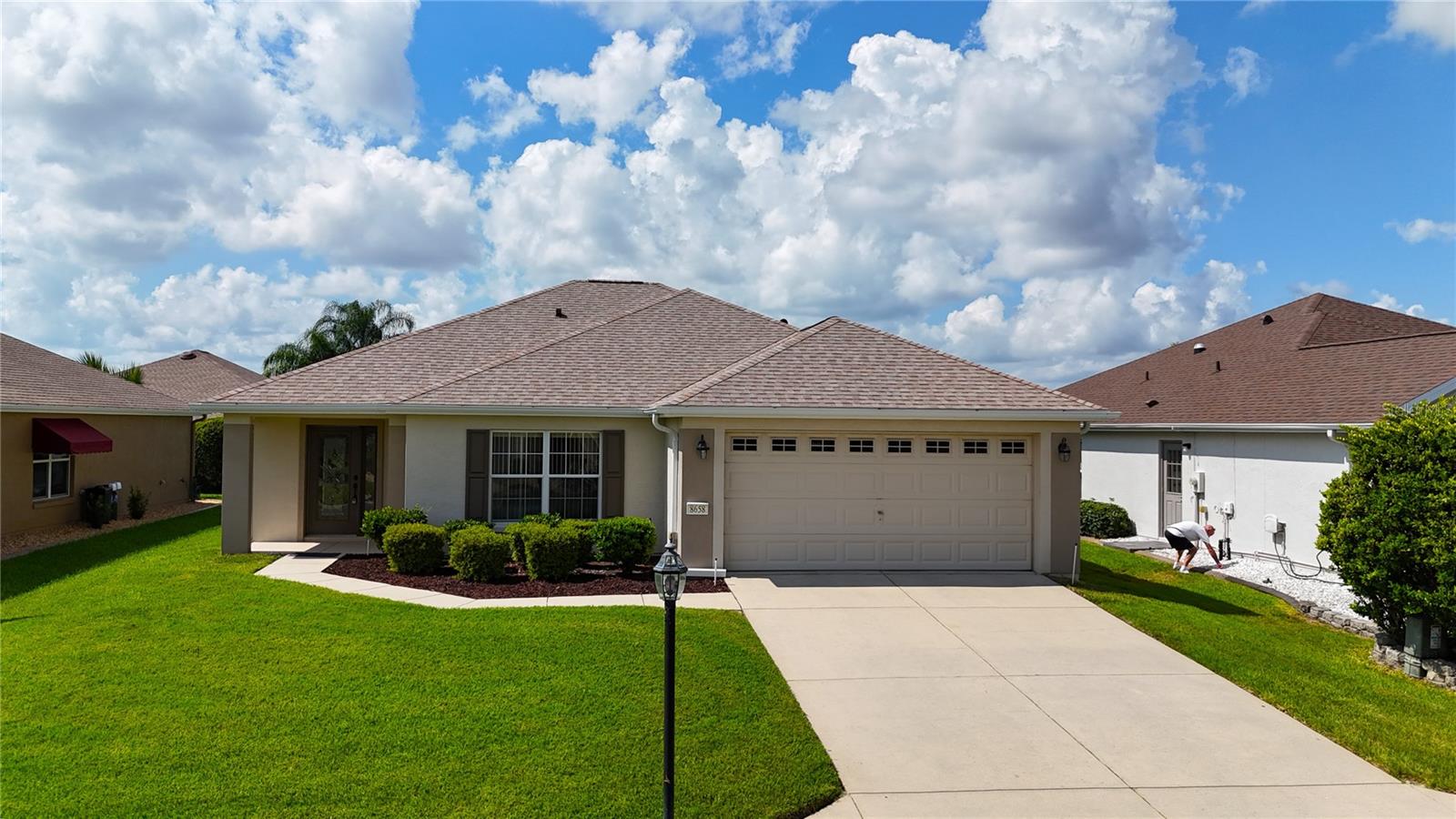 Start planning your winter retreat with this concrete block and stucco, two bedrooms, two baths plus a two car garage with key-less entry. Garage door has window inserts giving one natural lighting during the day. Great curb appeal and features low maintenance landscaping. Beautiful designer door with matching side window. Heavy traffic areas have tile while the bedrooms are carpeted. Eat-in kitchen with closet pantry and breakfast bar. Triple slider to the screened in lanai. Inside laundry room complete with washer and dryer and overhead storage cabinetry. Primary bath is equipped with double vanities, large shower with sliding frosted doors and a water closet. Home is partially furnished and will go with the house so what you see is what you get. New shingles December 2024. Great price for this great home centrally located within the community.