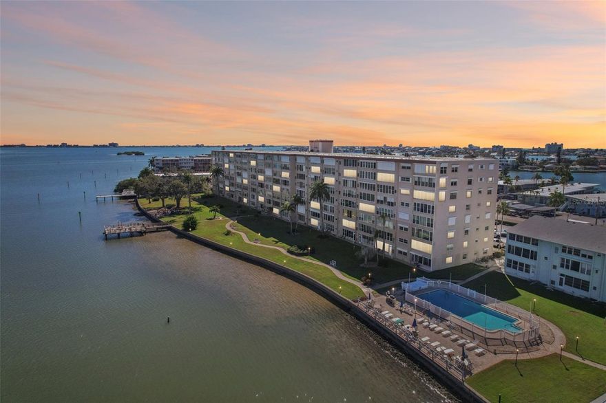 Experience the ultimate Florida lifestyle with this beautifully updated maintenance free 55+ waterfront condo in the heart of South Pasadena. From the moment you wake up, you are greeted with stunning panoramic views over Boca Ciega Bay that follow you from the kitchen sink all the way through the living space and into the sunroom. This 1050 square foot condo features 2 bedrooms and 1 bathroom and has been thoughtfully updated for peace of mind and comfort. The living room showcases custom built-ins and opens to a window lined sunroom that creates the perfect place to relax while watching dolphins glide by. The primary bedroom offers an oversized walk in closet for easy organization and storage. Recent improvements include the installation of hurricane impact windows in the sunroom in 2024, along with solar shades for added comfort and efficiency. Storm shutters were added to the kitchen and bedroom windows in 2005, and new blinds were installed in the kitchen and foyer in 2022. The AC and heat system were replaced in 2020, and a new energy star refrigerator was added in 2023. These thoughtful upgrades showcase the consistent care and attention given to this condo. This condo includes its own assigned parking space with plenty of guest parking available. The Shore Crest community provides an unmatched waterfront lifestyle with a wide array of amenities including two heated pools, a clubhouse, fitness center, library, shuffleboard courts, a kayak launch, extensive waterfront seating areas, gas grills, and two fishing piers including a newly completed pier in 2023. Shared storage areas on each floor make it easy to store beach gear and bikes. This active 55 plus community does not allow pets or rentals which creates a peaceful atmosphere and a friendly neighborhood feel. All milestone inspections were completed and funded in 2023 and a fully funded roof replacement was completed in 2025 for added peace of mind. Residents enjoy two laundry rooms in the building, one on the first floor and another conveniently located on the fifth floor. The location is truly unbeatable with walking distance access to two marinas for chartering a boat, nearby shopping, dining, a winery, bowling, and the popular St. Pete Beach Sunday Market. With the Sunrunner bus just minutes away, you can leave the car behind and enjoy easy transportation to downtown St. Pete or St. Pete Beach. Schedule your showing today and experience firsthand everything this exceptional waterfront community has to offer.