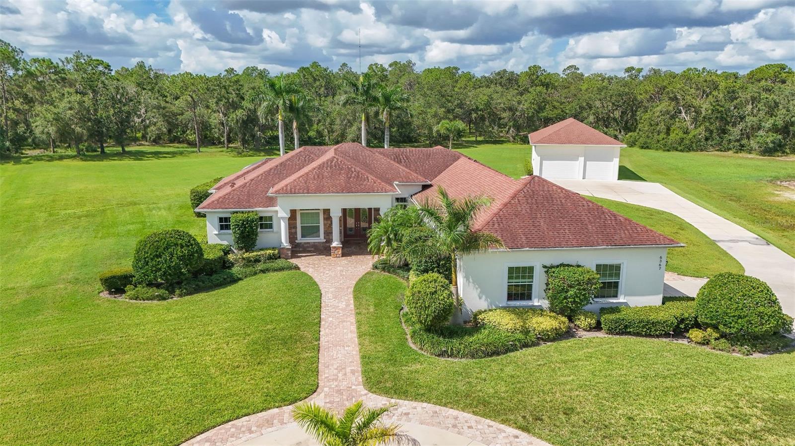 Luxurious 4-Bedroom Pool Home on 5 Acres with an Incredible 2,000 Sq. Ft. Outbuilding!
This custom-built (2014) 4-bedroom, 3-bath home plus office built by Johnson, sits on a premium cul-de-sac lot in Foxbrook, offering privacy and dry land— The house features all impact-resistant windows and sliders, ensuring durability and peace of mind. The attic and walls are fully insulated with spray foam for maximum energy efficiency.
The Ultimate Outbuilding – Garage, Workshop, Guest House? You Decide.
An absolute dream for car collectors, RV or boat owners, mechanics, or hobbyists, this property features a 2,000 sq. ft. custom outbuilding that’s as versatile as it is impressive. Built with 15-ft ceilings, hurricane-rated windows and doors, full spray-foam insulation, a 5-ton A/C unit, and 100-amp electric service, it delivers both industrial-grade durability and residential-level comfort. Currently set up as the ultimate climate-controlled garage or workshop, this space also offers incredible potential for conversion into a guest house, private apartment, home office, or in-law suite. With the right finishing touches, it could become a separate living quarters — ideal for multigenerational families, visiting guests, or even short-term rental income.
Enjoy a heated saltwater pool, resurfaced in 2023, along with a 3 person hot tub that stays with the home. The outdoor kitchen overlooks a wooded backyard with wide paths and trails, perfect for off-road fun. The property is horse-friendly, surrounded by abundant wildlife, and features a whole-yard irrigation system on well water, while the home runs on city water with a septic tank. The home also includes a new hot water tank installed in 2023.
Located within the Foxbrook community, residents enjoy amenities such as a basketball court and playground. With its high-and-dry elevation, this rare estate presents endless possibilities—schedule your private showing today!