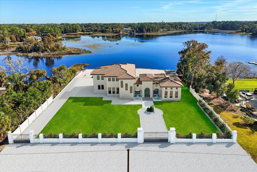 Under Construction. Expected completion Feb 2026. Welcome to an extraordinary lakefront opportunity on Little Lake Mary, one of Lake Mary’s most coveted private waterfront enclaves. This custom-built luxury estate spans approx. 7,000 sq ft and sits on over an acre of prime lakefront, offering expansive shoreline, unobstructed water views, a private boat ramp, and a lifestyle that blends privacy and sophistication. Opportunities of this caliber within the highly sought-after 32746 zip code are exceptionally rare.

Designed as the seller’s forever dream home, the residence was thoughtfully planned and built with intention, legacy, and timeless luxury. As family needs have evolved, this creates a rare opportunity for a new owner to step into a home crafted without shortcuts or resale in mind. The home offers up to five bedrooms and four baths, including two primary suites—one on each level—ideal for multigenerational living or elevated guest accommodations, with elevator access between floors.

The downstairs primary suite is a private retreat featuring a fireplace, luxury sauna, spa-style bathroom, and direct access to outdoor living areas, while the upstairs primary suite captures sweeping lake views and opens to a private balcony. Indoor and outdoor living flow effortlessly through a grand open-concept great room with soaring ceilings, expansive chef’s kitchen, and thoughtfully placed windows that fill the home with natural light while framing tranquil lake views.

An oversized golf simulation room offers flexibility as a golf studio, media room, private lounge, or customized recreational space. Outdoors, the estate is anchored by a resort-style pool and elevated spa with dramatic water features and lake views, complemented by an expansive covered living area with outdoor kitchen, bar seating, multiple entertaining zones, and a dedicated fire pit lounge.

A private gated entrance opens to a substantial driveway designed to accommodate multiple vehicles and gatherings. A large detached flex building offers versatility as a private gym, studio, home office, creative space, or potential in-law suite, while preserving the privacy of the main residence.

The home is at an ideal stage of completion, offering the rare opportunity for buyer input on select final design elements including flooring, kitchen and bath countertops, select lighting, and front driveway and landscaping design—allowing personalization of a luxury lakefront estate without the extended timeline of starting from scratch.

Ideally positioned in Lake Mary near top-rated schools, downtown dining, parks, and major corridors including I-4 and 417. Little Lake Mary is treasured for its calm mornings, stunning sunsets, and the rare feeling of being tucked away while remaining centrally located. Opportunities offering over an acre of lakefront with this level of craftsmanship and personalization potential almost never come available. This is more than a home—it is a legacy lakefront lifestyle.