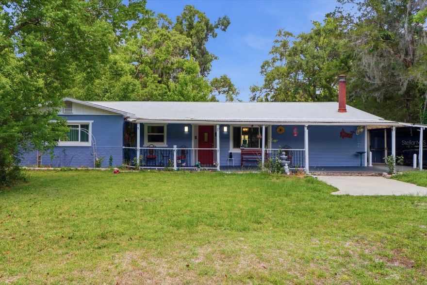 Tucked away in a quiet and serene setting in desirable Brooksville, this charming 2-bedroom, 2-bath ranch-style pool home offers the perfect blend of privacy, comfort, and country charm on a nearly 1.50-acre lot surrounded by mature trees. A gated driveway welcomes you home to an inviting front porch that sets the tone for this peaceful retreat. Inside, you’ll find an open-concept floor plan with luxury vinyl plank flooring throughout and no carpet anywhere in the home, a cozy corner wood-burning stove with stunning stone surround, and a separate dining area ideal for entertaining. The kitchen features granite countertops, tile backsplash, stainless steel appliances, breakfast bar/island seating, and French doors leading directly to the pool area for effortless indoor-outdoor living. The guest bathroom has been tastefully renovated with a tub/shower combo and glass doors, while the spacious primary suite offers built-in closet features, wainscoting, and an updated ensuite bath complete with dual sinks, soaking tub, and walk-in glass shower. Enjoy relaxing or entertaining on the covered back porch overlooking the sparkling pool and tranquil backyard views. Additional highlights include a large laundry room, carport, and extra outbuilding for storage, hobbies, or workspace. A rare opportunity to enjoy peaceful Florida living with space, privacy, and modern updates just minutes from everything Brooksville has to offer.