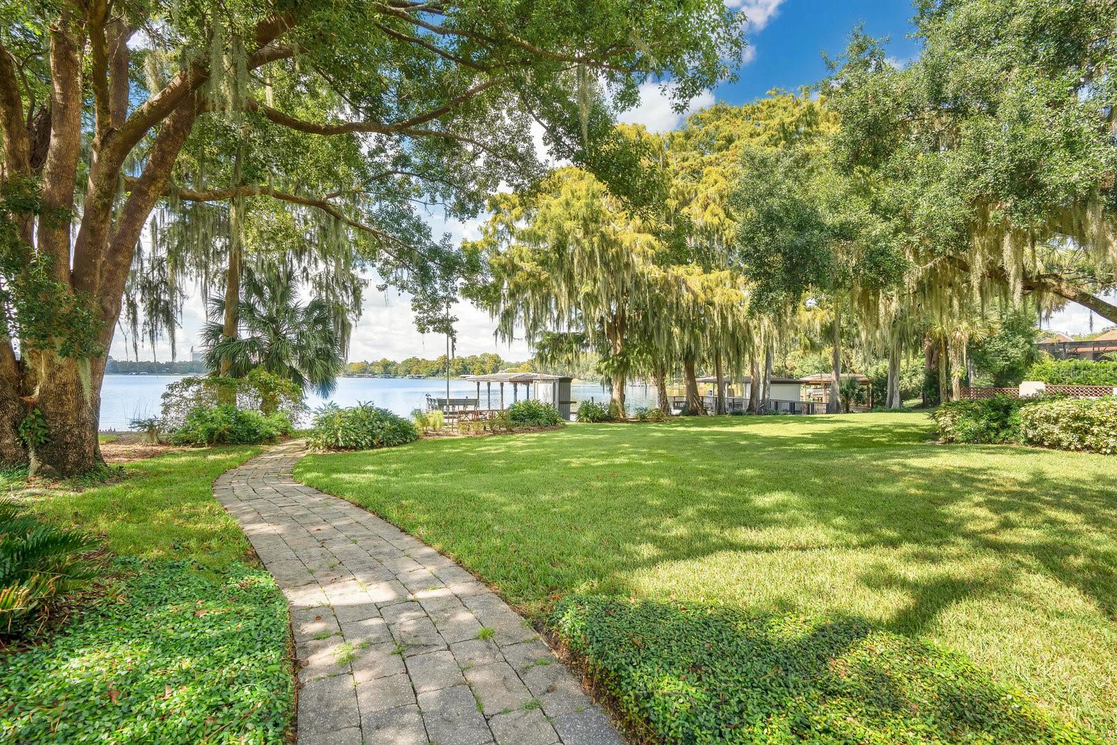 Just Listed ~ Stunning lakefront home in Winter Park that has been completely remodeled and offers 4 bedrooms, a bonus room, and guest apartment! This home is exquisite from top to bottom and features elevated ceilings, crown moldings, designer fixtures and wall coverings. Large picture windows overlook Lake Sue from the living room, dining room, and kitchen. The kitchen is gorgeous and offers chef-grade appliances, a large center island, plenty of soft-closed cabinetry for storage, and an open-concept layout for inclusive entertaining. French doors open off the family room to seamlessly blend the indoor/outdoor living space. A covered lanai with outdoor kitchen overlooks the beautiful, resort-inspired, heated pool and spa, multi-level summer terrace with gardens, and the custom 3-hole putting course. Back inside, located on the 2nd floor, the primary suite has a Juliette balcony that overlooks the shores of Lake Sue and features an en suite bath with a double-headed shower, separate soaking tub and double-sink vanity. An oversized guest suite with private bath and two bedrooms and a hall bath complete the second floors. On the first floor is a bonus room (ideal for use as a playroom, home office, or studio), a full bath, and laundry room. Above the detached 2-car garage is an apartment with a kitchenette and full bath with walk-in shower. The expansive 0.58 acre property extends over the charming brick street and includes a large, park-like green space, shaded beneath majestic oaks, s small beach area, elongated dock, and boathouse (no lift). Located within minutes of Park Avenue, this lakefront estate is a short walk or bike ride to nearby shops and dining and is zoned for one of the best school districts in the area. Audubon Park, Baldwin Park, the Mills District, and Downtown Orlando are all within a 10-minute drive. Showings are by appointment only – schedule yours today.