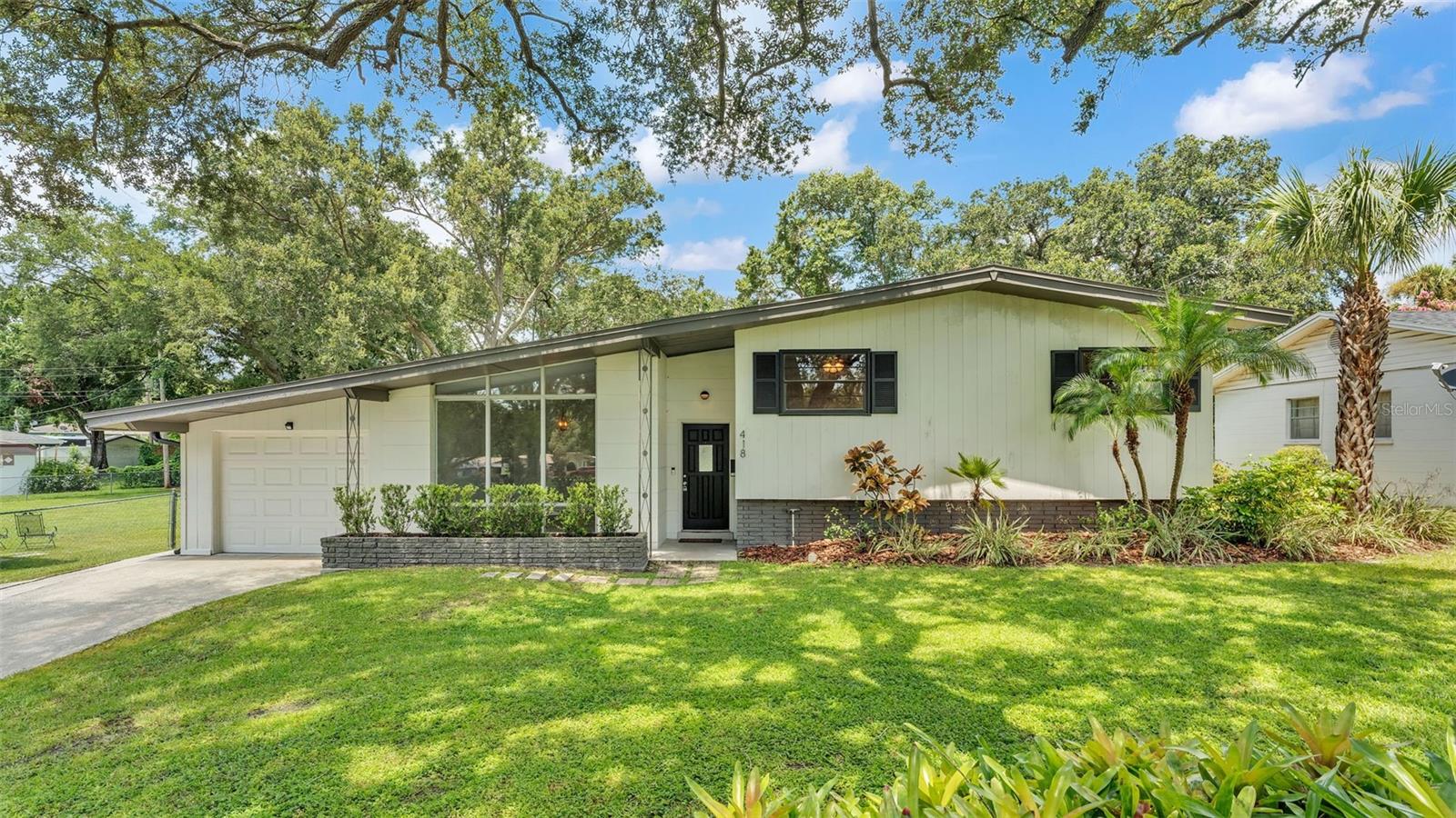 Welcome to this beautifully updated Mid-Century Modern gem, ideally located in Central Lakeland with unmatched convenience to South Florida Avenue, the Polk Parkway, and just minutes from downtown Lakeland and the scenic shores of Lake Hollingsworth. Move-in ready and freshly repainted throughout, the home features a full interior repaint of walls and trim completed in July 2025, offering a bright, modern feel that’s truly turnkey. This thoughtfully renovated residence boasts three spacious bedrooms and three full bathrooms, including a private ensuite primary bath with a walk-in tiled shower. Two additional bedrooms are located upstairs, each with access to a full bathroom, providing comfort and privacy for family or guests. On the main level, you’ll find a third full bathroom and an abundantly sized flex room that overlooks the screened-in pool. This versatile space features several sliding glass doors that flood the room with natural light and create seamless indoor-outdoor living. The heart of the home is the stylishly remodeled kitchen, which showcases granite countertops, subway tile backsplash, a pass-through window to the lanai, and a cozy breakfast nook. The kitchen also features newly installed upgraded cabinetry with decorative upper trim and matching Frigidaire stainless steel appliances. Vaulted ceilings in the formal living and dining rooms enhance the open layout, while polished tile flooring, modern elegant light fixtures with bronze and gold accents, and refinished hardwood floors in the bedrooms add warmth and sophistication. The outdoor space is just as impressive, sitting on a fully fenced 0.47-acre lot—the largest in the neighborhood. A beautifully landscaped perimeter ensures privacy, and the large front and back yards offer plenty of space for relaxation and play. The screened-in pool and lanai are perfect for entertaining, with direct access from the family room and flex space. Additional upgrades include a new garage door with side yard access, mature landscaping with fresh mulch, and a new water heater installed in 2019. With its spacious layout, stylish upgrades, and unbeatable location, this one-of-a-kind home offers the perfect blend of classic charm and modern convenience. Don’t miss your chance—schedule your private showing today!