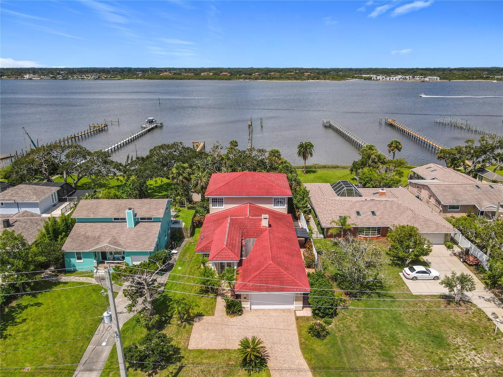 One or more photo(s) has been virtually staged. Dream luxury waterfront estate nestled along the scenic Halifax River. 2306 S Halifax Drive in Daytona Beach is a stunning two-story block home offering 60 feet of direct waterfront on a sprawling half-acre lot with no HOA. Boasting just under 4,000 square feet, this residence is a true entertainer's dream and a serene retreat all in one. Step inside to an expansive open floor plan featuring a blend of hardwood, tile, and laminate flooring, a wet bar with granite countertops, butler's pantry and grand formal living and dining areas that showcase breathtaking water views through oversized windows. The gourmet kitchen flows seamlessly into the main living spaces, creating the perfect setup for gatherings. The home offers 4 spacious bedrooms, 4.5 bathrooms, and the 4th Bedroom makes the perfect In-Law Suite, Office or Gym with its own private entrance and nearby full bathroom. The laundry room is conveniently located inside. Retreat upstairs to your Private Primary Suite with a Den, occupying the entire second floor! Enjoy the walk-in shower with Kohler Steam, soaking tub, generous closet space, and your own balcony with panoramic views of the river and peaceful spot to start or end your day. Interior features include plantation shutters, tray ceilings, wood burning fireplace and beautifully crafted columns with a grand staircase exiting to the backyard. On the outside, the paver driveway, clay tile roof, and mature landscaping add to the home's curb appeal. Enjoy coffee on your private balcony or exit the double French doors to your direct waterfront! The river provides navigable access to the open waterway in the Atlantic Ocean. Located 3 miles to the Daytona Pier and 6 miles to the International Speedway plus the beach, dining, shopping, and entertainment are all nearby! This home is perfect for those who want to enjoy the ultimate coastal lifestyle. Rental restriction is 6 months, for those seeking an investment opportunity! Don't miss this rare opportunity to own a piece of paradise on the Halifax River!