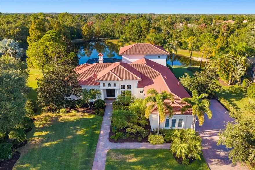 A rare sanctuary of architectural grace and unrivaled privacy in one of the most prestigious enclaves of Lakewood Ranch Country Club. Offered turnkey furnished, this distinguished two-story estate is perfectly positioned on over a half-acre with unobstructed views of the lake and protected preserve -- no neighboring homes in sight. The grand herringbone-patterned paver walkway and extended driveway with a side-entry three-car garage set a tone of timeless sophistication.
Hurricane-rated fiberglass double entry doors, crafted to emulate wrought iron, open to more than 4,800 sq ft of refined living space adorned with travertine flooring, Corinthian columns, and sweeping water views. Four separate bedroom suites with walk-in closets, a dedicated office, living room fireplace, 14-foot dining ceilings, and a family room. A large flex room offers versatility for a theater, gym, or game retreat, while the laundry room's window fills the large workspace with natural light. Abundant storage. 
Upstairs, a bonus room with wet bar and private guest suite capture panoramic views of the lake, woods, and  abundant wildlife. Outdoors, the pool, spa, outdoor kitchen and shower offer total seclusion, completing this exceptional home where timeless architecture facilitates complete tranquility.