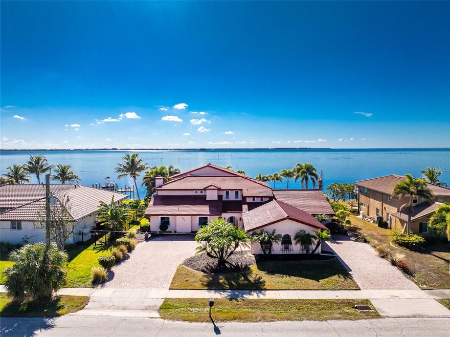 Unmatched harbor views, endless potential, and a true boater’s paradise. This exceptional waterfront estate offers breathtaking, million-dollar panoramic views of Charlotte Harbor and an incredible opportunity to create a custom luxury retreat. Featuring 5 bedrooms, 4.5 bathrooms, and approximately 6,100 sq ft of living space, this home is positioned to capture stunning water views from nearly every angle. Recent upgrades include brand-new flooring and bathroom vanities (2025), a brand-new dock, and a fully restored retaining wall, giving peace of mind and immediate value. The lower level has been completely gutted following storm damage from Hurricanes Milton and Helene, with drywall removed and flooring stripped—providing a blank canvas ready for your vision and design. The main level offers four spacious bedrooms, while the second floor is dedicated to the private primary suite and an expansive bonus room wrapped in windows, showcasing unforgettable harbor views. An elevator provides convenient access between levels, and the unique dual drive-through driveway and garage allows access from either side of the property. Additional features include a tile roof (2018), newer A/C systems (2019), hurricane-impact windows and sliders throughout, public water and sewer, and no bridge access, making this an ideal property for any size vessel. Perfectly located just minutes to restaurants, shopping, and downtown Punta Gorda, and under 30 minutes to Englewood Beach and Boca Grande, this home is priced below market value, leaving substantial room for renovation, customization, and future equity. Rare views. Prime location. Unlimited potential. Don’t miss this opportunity to transform a remarkable waterfront property into a true Charlotte Harbor showpiece.