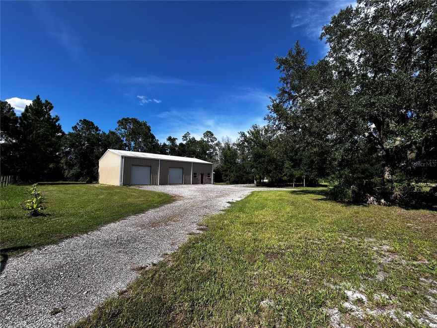 15401 County Road 450 is a slice of natural paradise with nearly infinite future possibilities. Perfect parcel for a custom home, an agricultural business, or do both!  Of the 9.46 total acres, 5.86 acres are 'Zone X' dry land, while 3.60 acres are part of a larger wooded wetlands. The wetlands begin at the tree line to the north (rear) of the property. This green space, which includes a tranquil pond, offers excellent privacy at the rear of the property.  On the West end sits a 40' x 60' red-iron metal building, accessible easily by a gate on LeGrande St that enters into a gravel parking area. A 12 x 15 insulated office (drywall interior, plywood facing warehouse) is constructed in the building, plus a 12kBTU minisplit AC installed in 2024 to handle office heating and cooling.  The remainder of the building is unfinished clear-span construction with a concrete slab floor and a 200a electrical subpanel. 14' eaves, front & rear pedestrian doors, and three 10' tall roll up doors (3rd roll up door not pictured, faces bathroom building). Near the metal building is a small accessory building with a full bathroom (including shower), plus a utility room with water heater and washer/dryer connections. Power is run underground from the street frontage to the backside of the building, no overhead power lines enter the property! Meter and main shut-off panel on rear of building, 200a subpanel inside building.  The building has 200amp service, while the drop from the pole to the meter was intentionally oversized in order to adequately service at least 400a service to allow for a future 200a house service without the need for a new primary utility connection.  The well was drilled new in 2015 with water run to the steel building, accessory building, and in a loop to various hose spigots scattered around the property.  There's a shaded gravel RV pad (approximately 12'x60') extending from gravel parking area, 50amp electrical, water, and sewer connection for RV.  Plans were submitted in 2016 to build a 2500sf home, impact fees paid, perk tests performed, but ultimately the house wasn't built and permits cancelled.  The impact fees paid will reduce or eliminate additional impact fees for new construction, verify details with county.  15 loads of fill dirt were spread in the field towards the East to level & elevate the homesite location. The dirt has naturally compacted while sitting in place for 8+ years.   There is gate to access the gravel parking area from LeGrande St, plus an additional gate directly on CR 450 frontage. The plan was to build a home on the Eastern side of the parcel, visually separating the home from the shop. No active/open permits exist, future home & homesite specifics are fully up to the buyer. This land is set up perfectly to build your dream home with plenty of room for dry materials storage during construction in the 2400sf building.  Use the building for personal or business use in the future. In addition to water and power already being in place, Lake county allows property owners to live in an RV on-site, as long as they have active permits to construct a home on-site.  Once the home is completed, long-term living in the RV is no longer allowed, though short term guests are generally OK.  Park your RV for an immediate home-base while building your dream home!  Surrounding homes are of various sizes and designs, all on larger parcels.  Convenient to Mt. Dora, Eustis, and The Villages.  Schedule a tour today!