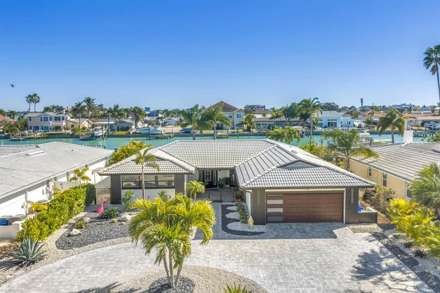 This exceptional waterfront residence, rebuilt in 2024/2025, delivers a refined blend of modern design, advanced technology, and sweeping open canal water views. Thoughtfully enhanced over time and constructed with quality and longevity in mind by professional contractors, this three-bedroom property offers an exceptional coastal lifestyle in one of Treasure Island's / St. Petersburg's most desirable waterfront settings "Isle of Capri". Spanning approximately 2336 square feet, the home features three bedrooms, two full bathrooms, travertine flooring throughout, a flexible split bedroom layout designed for everyday living and entertaining. The main living area welcomes you with a spacious formal living room, great room anchored by striking expansive windows capturing the water beyond. An open-concept design flows seamlessly into the dining and kitchen areas, creating a refined backdrop for living and entertaining. The kitchen is a true showpiece with a massive waterfall-edge island featuring professional-grade induction cooktop, stainless steel bottom mount freezer refrigerator for a seamless custom look, and expansive European-style cabinetry. Quartz countertops and thoughtful design details elevate the space, while an oversized walk-in laundry offers convenient additional storage space. A private glass enclosed office space is a room with views of the home and the water combined. The master suite, the primary retreat serves as a true sanctuary with a custom spa-inspired bathroom featuring a large walk-in shower and ample size suite. Additional upgrades include motorized garage privacy screen, Epoxy flooring, storage cabinets, recently installed NEW flat roof, New AC, New Hot water Tank, New Composite Dock, Paver driveway and walkway and so much more.   The Outdoor living is exceptional, with incredible water views, a composite dock with sitting bench and swim ladder. The resort style back yard offers enough space for a fantastic, pool if the new owners so desire. The thoughtfully designed landscaping and new fencing provide privacy and security without sacrificing the waterfront backdrop. Additional highlights include impact-rated windows and doors throughout, offering enhanced storm protection and peace of mind, along with an oversized garage providing exceptional space for multiple vehicles, storage, and toys. Perfectly positioned in Treasure Island, Isle of Capri, the home offers easy golf-cart access to all that the World-Famous Beaches and the islands have to offer known for its waterfront dining, award-winning restaurants, parks, and year-round events. This is a rare opportunity to own a meticulously upgraded waterfront home that combines modern luxury, smart-home innovation, and timeless coastal appeal.  Don't let this property pass you by.