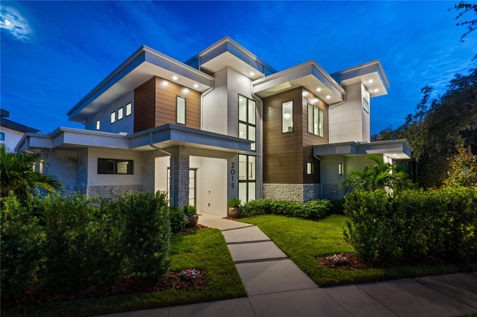 Boasting a prestigious Park Avenue address, this striking modern architectural residence perfectly balances bold design with spa-like serenity. Set on a beautifully landscaped corner lot, the home embodies the rare combination of privacy and proximity, just a leisurely 25-minute stroll from Park Avenue’s world-class boutiques and dining. Every element of the design has been meticulously curated to evoke a sense of refined tranquility, where clean lines, natural textures, and warm tones create a timeless yet inviting atmosphere. Inside, expansive open concept living spaces are bathed in natural light, showcasing designer lighting, custom millwork, and seamless indoor-outdoor integration. The chef’s kitchen is a true centerpiece, anchored by dramatic quartz countertops, sleek custom cabinetry, and top-tier stainless steel appliances, complemented by a hidden walk-in pantry that enhances both style and function. The main living area opens effortlessly to the pool creating a fluid connection between indoor elegance and alfresco entertaining. The primary suite is a private retreat defined by calm sophistication offering a spa-inspired bath with a massive walk-in shower featuring multiple shower heads, a freestanding soaking tub, dual vanities, and a custom closet that feels like a boutique dressing room. Upstairs, a loft serves as a serene media or lounge area, while three spacious ensuite bedrooms provide comfort and privacy for family and guests. A dedicated home office continues the home’s minimalist aesthetic, fostering focus in a tranquil setting. Outdoors, the property unfolds into a private resort-like sanctuary with a sparkling pool, lush landscaping, and a fully equipped summer kitchen designed for seamless entertainment. A newly added rooftop deck serves as an architectural statement piece, connected by a spiral staircase that descends to the backyard below. The detached gym offers flexibility as a fitness studio, guest suite, game room, or creative workspace. From its sleek modern lines to its spa-like finishes, this home captures the essence of elevated Winter Park Living. A short walk to Winter Park Village and downtown WP puts you right in the middle of everything.