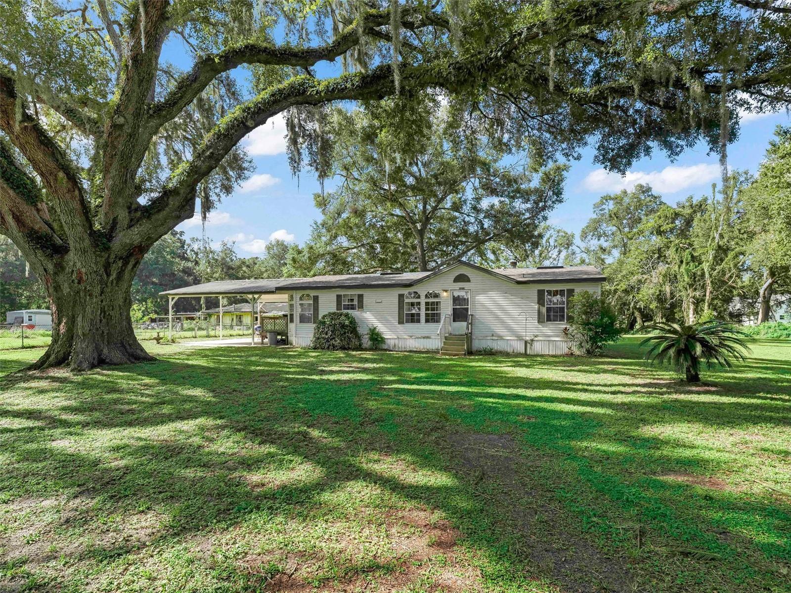 Experience the perfect blend of comfort, charm, and convenience in this beautifully maintained 3-bedroom, 2-bath mobile home offering 1,248 sq. ft. of inviting living space on a peaceful 1-acre lot. Nestled by a majestic grandfather oak that provides natural shade and privacy, this home welcomes you with a warm, cozy living room featuring a rock-framed gas fireplace—ideal for Florida’s cooler evenings. The formal dining room sets the stage for memorable gatherings, while the bright kitchen offers a charming breakfast nook and generous cabinet space. Stylish luxury vinyl flooring flows throughout the home, offering both elegance and durability. Step outside to unwind on the porch, enjoy the convenience of a covered carport, and take advantage of multiple sheds for all your storage needs. Recent updates provide peace of mind. Per the Seller, the updates include: a new shingle roof (2023), a 3-ton central HVAC system (2022), updated drainfield (2020), and a brand-new well pump and tank (2024). Located just over 3 miles from downtown Bushnell with quick access to I-75 and U.S. 301, this home offers an easy commute to Tampa, Orlando, and The Villages. With shopping, dining, and medical services all close by. Whether you're looking for a serene full-time residence or a relaxing weekend escape, this charming property is ready to welcome you home. Schedule your private tour today!