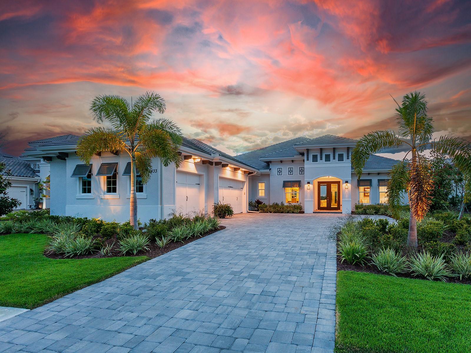 Sleek and modern, this lakefront 2022-built home is a masterpiece highlighting western views for the most stunning sunsets. Built by Stock Signature Homes, this like-new residence has 4 true bedrooms (each can handle King Size Beds, PLUS 3 are ensuite), 4 bathrooms, PLUS a study…PLUS a bonus room in over 3,700 square feet of carefully selected upgrades and quality construction. From the meticulous landscaping to the long paver driveway with parking pad and side entry garages, you will be welcomed into a large and inviting foyer through double glass front doors where you are greeted with immediate views of the lake and the preserve beyond. The light and bright color palette with warm accents is the perfect backdrop for any design and lifestyle and truly highlights the remarkable blues of the lake and lush greens of the Florida landscaping. The expansive great room features a custom LED backlit, drop-down ceiling with tray and 10’ impact sliding glass doors to the lanai. The open kitchen invites guests to gather around the large central island while the chef prepares culinary delights amongst warm wood cabinetry, 2024 built in Sub-Zero frig, 2022 appliance suite with two ovens, quartz counters and a walk-in pantry with shelving. Just off the kitchen is a convenient dry bar with additional storage and wine refrigerator. Choose your own adventure in dining between the formal dining room or the casual dinette, or even dine alfresco on the lanai. The lanai will be your paradise at home with a large covered entertaining area with tray ceiling, you can gather around the custom fireplace on cozy nights; or bask in the sunshine on the side patio. Impressive views will abound no matter where you choose to spend your time with over 80’ of lake views through wide screen panoramic screen enclosure. The heated saltwater pool and spa is perfectly positioned to take advantage of the views, especially from the raised spa, while still being near the action. Outdoor meals are easily prepared at the outdoor kitchen with stainless grill, bar refrigerator and nearby access to the kitchen. The primary suite offers the same bright palette and impressive tray ceilings, plus French doors with transom windows to the lanai and lake views. Pass by dual walk-in closets with custom cabinetry on your way to the primary bathroom with freestanding soaking tub, spacious walk-in shower with frameless glass enclosure, vanity with dual sinks and private water closet. The rear bonus room offers a flexible space for a media room, second office or 5th bedroom, plus oversized windows with extra transoms above for lots of natural light and to maximize the lake and preserve views. Guests will enjoy their own comfy accommodations with 3 guest bedrooms all with walk-in closets, two of which have ensuite bathrooms and there is an additional guest bathroom that also functions as a pool bath. Rounding out this impressive home is a stately study with double French doors (currently used as a formal living room), and laundry room with plenty of counterspace and cabinets. Peace of mind will be found in the impact windows and sliding doors throughout the home, plus tankless water heater and recent home construction. The Lake Club is a premier, private gated community including a Grande Clubhouse, restaurant, pool, tennis, pickleball, playground, basketball, Linear Park, fitness center, dog park and interlinking lakes for kayaking or fishing. Start living the dream life you’ve always wanted!